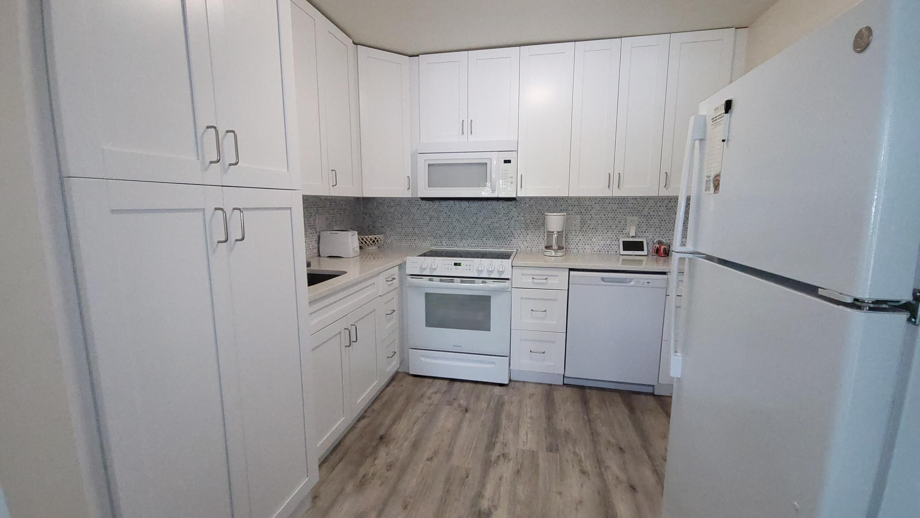 Inviting, light-filled, and impeccably renovated extra-large 1-bedroom, 2-bath residence with serene views. This immaculate second-floor unit features impact windows throughout, luxury waterproof vinyl flooring, elegant quartz countertops, newer appliances, central air conditioning, a spacious walk-in closet, and the rare convenience of two full bathrooms plus a full-size washer and dryer.  The generously sized bedroom offers custom walk-in closet cabinetry and a beautifully renovated en-suite bathroom with a walk-in shower. The stylish guest bathroom features an oversized soaking tub, perfect for relaxation. Ideally located near the clubhouse and Hastings Fitness Center. This well-maintained building is part of a professionally managed association with water and basic cable included in the monthly dues. Assigned parking and ample guest parking are available. Residents also enjoy convenient private bus service for shopping and errands both within and outside the community.  Experience resort-style living in the highly desirable Century Village West Palm Beach, a gated 55+ community with 24-hour security and exceptional amenities. Residents enjoy a spectacular 92,000-square-foot clubhouse featuring a theater with live entertainment and free movies, fitness facilities, indoor and outdoor pools, billiards, card and craft rooms, library, dance and exercise classes, tennis, shuffleboard, bocce, and countless social activities. Courtesy transportation throughout the community and to nearby shopping, dining, and services adds to the convenience.  Ideally located just minutes from Palm Beach International Airport, Florida's Turnpike, I-95, downtown West Palm Beach, Rosemary Square, shopping, dining, and South Florida's beautiful beaches. Move-in ready and a must-see!