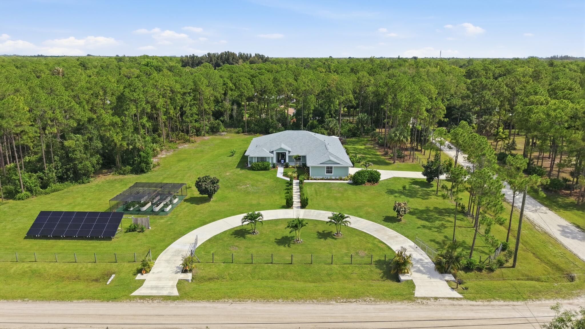 2021-built luxury CBS estate on 2.5 fully fenced acres in Jupiter Farms, where privacy, space and an equestrian-friendly lifestyle meet refined living. This 4BR/3BA + office home features soaring ceilings, 8-ft doors, crown molding, tile flooring, impact windows/sliders, a chef's kitchen with stainless appliances, gas range, wall oven and statement Williams Sonoma island. Enjoy a large screened porch, an outdoor living area with full summer kitchen, 3+ car garage with 50-amp charger, circular driveway, fully owned solar panels, 1,000-gal propane tank, RO/softened well water, security system with 9 Ring cameras, fruit trees, raised vegetable garden, fire pit and chicken coop. Room for barn, guest house and pool.