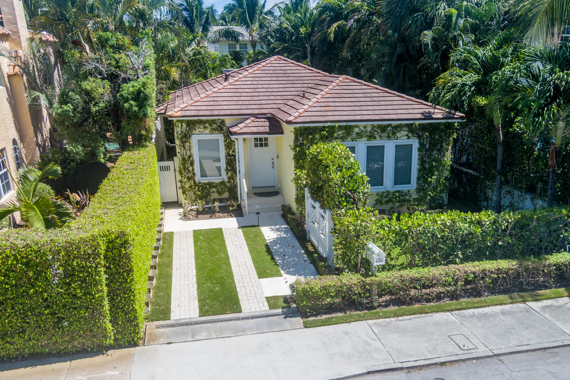 Palm Beach Gem. Welcome to this charming 2-bedroom, 2-bathroom Magnolia cottage, circa 1917, nestled in the heart of Palm Beach. The home exudes enduring character with crown molding, hand-painted hardwood floors, and custom built-ins. Large sliding glass doors in the dining/kitchen area provide an abundance of natural light, overlooking the heated pool/spa with jets and lights, and a tropical backyard curated by Mario Nievera. Impact windows and doors offer added security and peace of mind. In-wall speakers throughout the living room, kitchen, and exterior enhance your entertainment experience. Beach access and lake trail at either ends of the road create the epitome of island living as well as The Royal Poinciana Plaza, Lola 41, Cucina are within walking distance away.