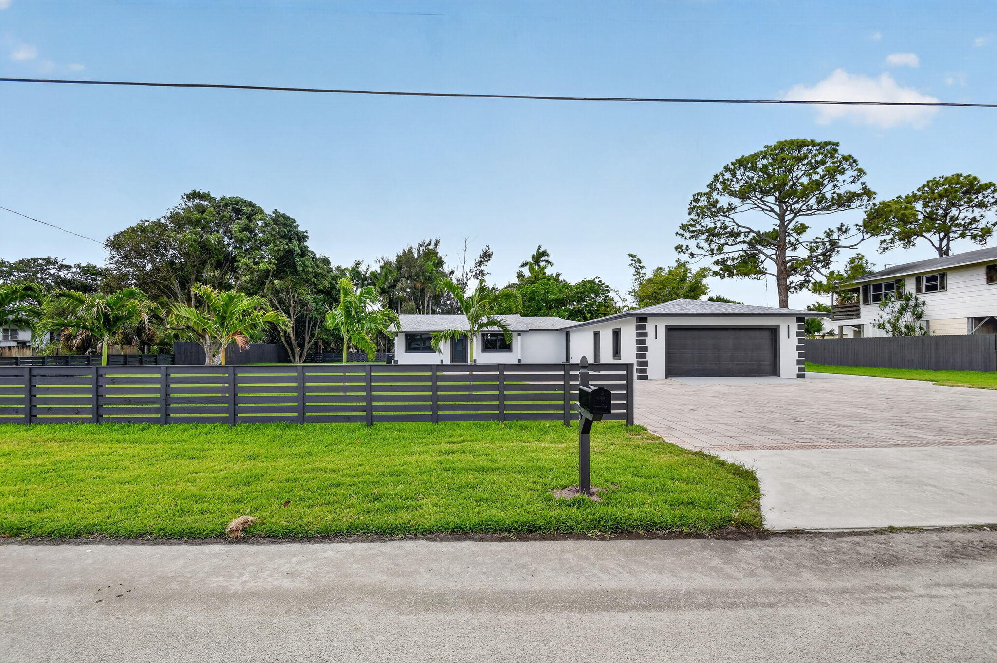 Stunning Fully Renovated 4-Bedroom, 3-Bathroom Modern Oasis with 3-Car Garage Welcome to this completely reimagined single-story home in West Palm Beach, where no detail has been overlooked. This turnkey residence offers a perfect blend of contemporary style, high-end finishes, and effortless Florida living. Step inside to an expansive, open-concept layout featuring sleek porcelain marble-look flooring, smooth high ceilings with recessed lighting, and a fresh neutral palette that creates a bright, airy atmosphere throughout. The gourmet kitchen is a showstopper with crisp white cabinetry, a large center island, premium quartz countertops, stainless steel appliances, and a stylish backsplash — ideal for both everyday meals and entertaining.  The spacious primary suite boasts a luxurious ensuite bathroom featuring a freestanding soaking tub, oversized walk-in shower, and dual vanity. The additional three bedrooms are generously sized, with two more beautifully updated full bathrooms. A convenient indoor laundry room completes the thoughtful floor plan. Outside, enjoy your private resort-style backyard backing to a serene canal. The expansive covered patio with rich wood ceilings offers the perfect shaded space for outdoor dining and relaxing while overlooking the lush, fully fenced yard. Additional highlights include a wide paver driveway, a massive 2-car garage, and beautiful curb appeal with modern black-and-white exterior finishes. This fully renovated home is move-in ready and perfectly located in West Palm Beach — close to shopping, dining, beaches, and major roadways. Whether you're looking for a primary residence or an investment property, this one checks every box. Schedule your private showing today and fall in love with your new home! All Measurments Are Only Estimates.