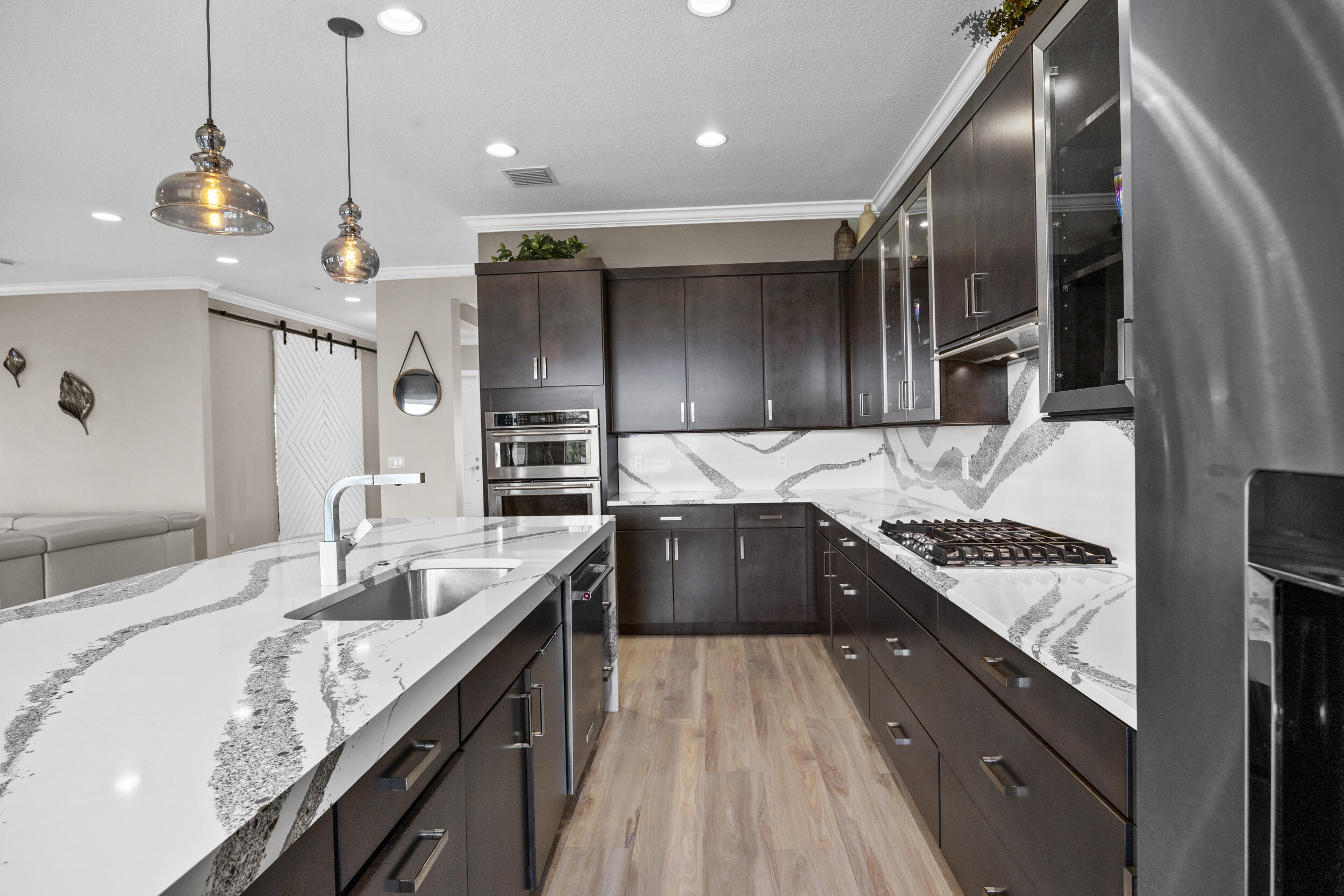 Skip the builder timeline and extra out-of-pocket costs with this 2021 Kenco-built lakefront home offering nearly 4,000 sq ft of move-in ready living. Soaring ceilings and natural light fill the space, anchored by a chef's kitchen with a large waterfall quartz island and gas range. Upgrades are already complete, including designer lighting, custom window treatments, and new flooring. A main-level ensuite bedroom plus an upstairs loft creates flexible living options. The rare 4-car garage sets this home apart. Step outside to a covered lanai with outdoor kitchen and a pool-ready backyard with new renderings available. Exceptional value in Arden without the wait.  Why build when perfection is ready today? Arden is South Florida's premier agrihood, offering a lifestyle that stands apart from anything else in the area. At the center of the community is a 5 acre working farm, where residents can enjoy fresh produce and seasonal harvests. Miles of scenic trails wind throughout, creating space for morning runs, evening walks, and time outdoors.  The amenities rival a private resort, featuring a striking two level pool with cascading waterfalls, a fully equipped fitness center, and a clubhouse that brings neighbors together through events and shared experiences.  Set along a 176 acre lake, Arden was designed for those who value space, fresh air, and a true sense of connection. All of this just minutes from Wellington's equestrian venues and the shopping and dining of West Palm Beach. Homes like this offer an opportunity to step into this lifestyle now, without the timeline or uncertainty of building.