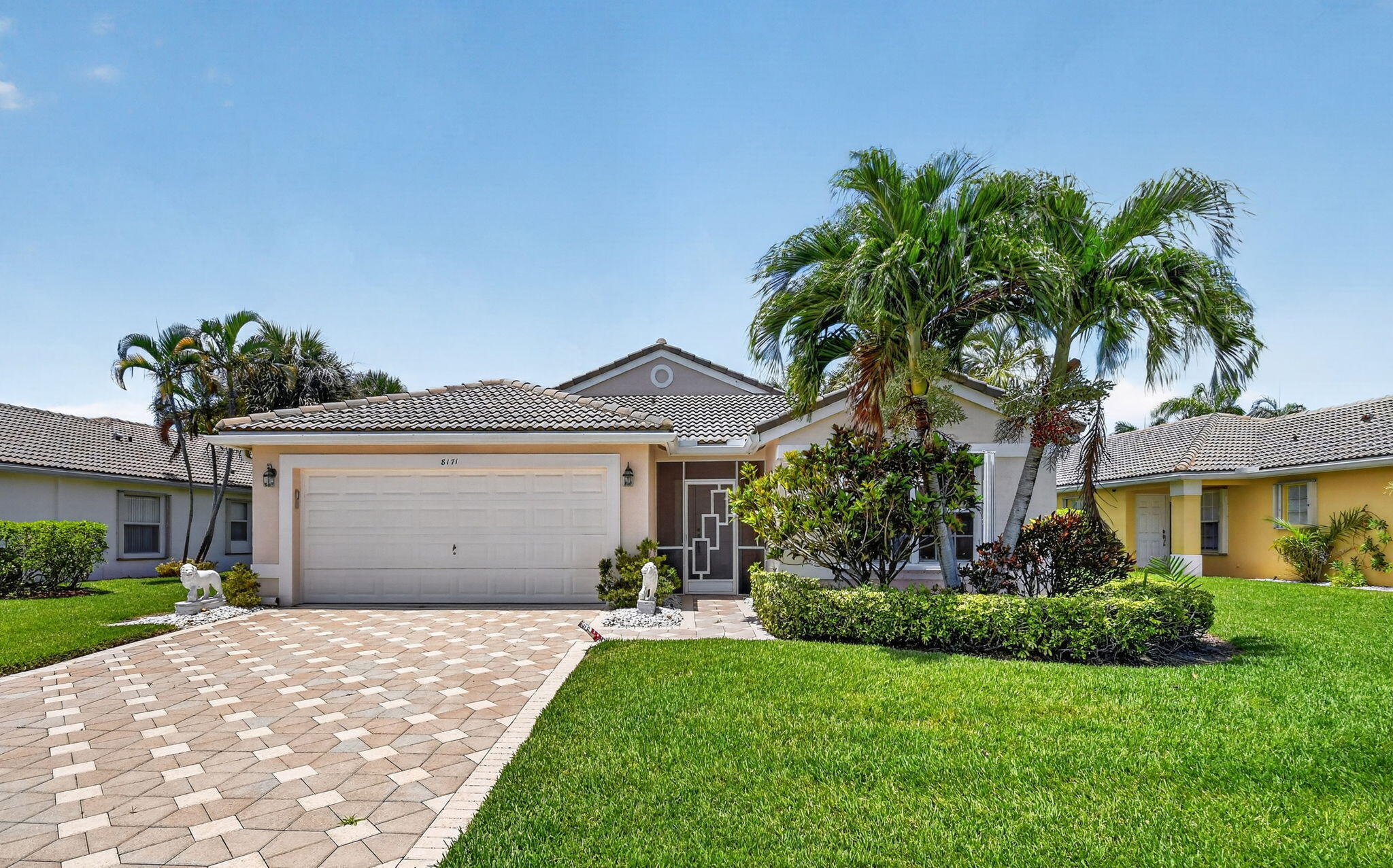 Welcome to Grande Palms, one of Boynton Beach's most sought-after gated communities, where tree-lined streets, sidewalks, a community pool, tennis court, and covered pavilion define the neighborhood lifestyle. This one-level, 3-bedroom, 2-bath single-family home sits on a 6,661 sq ft lot surrounded by mature privacy hedging and tropical landscaping.  The split bedroom floor plan opens into soaring vaulted ceilings & a spacious great room that flows directly to an oversized screened patio through dual sliders — one from the living room, one from the kitchen — a custom floor plan modification that sets this home apart. The patio is ceiling-fan equipped and looks out onto lush private greenery, making it a genuine year-round living place.   The closed kitchen features abundant cabinetry, a peninsula, and a sun-filled eat-in nook with garden views and direct patio access. The third bedroom is currently configured as a private office — ideal for today's work-from-home buyer and easily converted back to a full bedroom as needed.  The primary suite is generously scaled with two large walk-in closets, a linen closet, double vanities with makeup station, soaking tub, walk-in shower, a private toilet room, and glass block windows.   Storm protection is comprehensive: full hurricane shutters, hurricane-rated front and garage doors, and a screened entryway. The property carries a 4-point inspection and a 5-year roof certification. FEMA Flood Zone X: no flood insurance required. Pet friendly, up to 2 pets. Centrally located near Renaissance Commons with easy access to the Florida Turnpike and I-95.