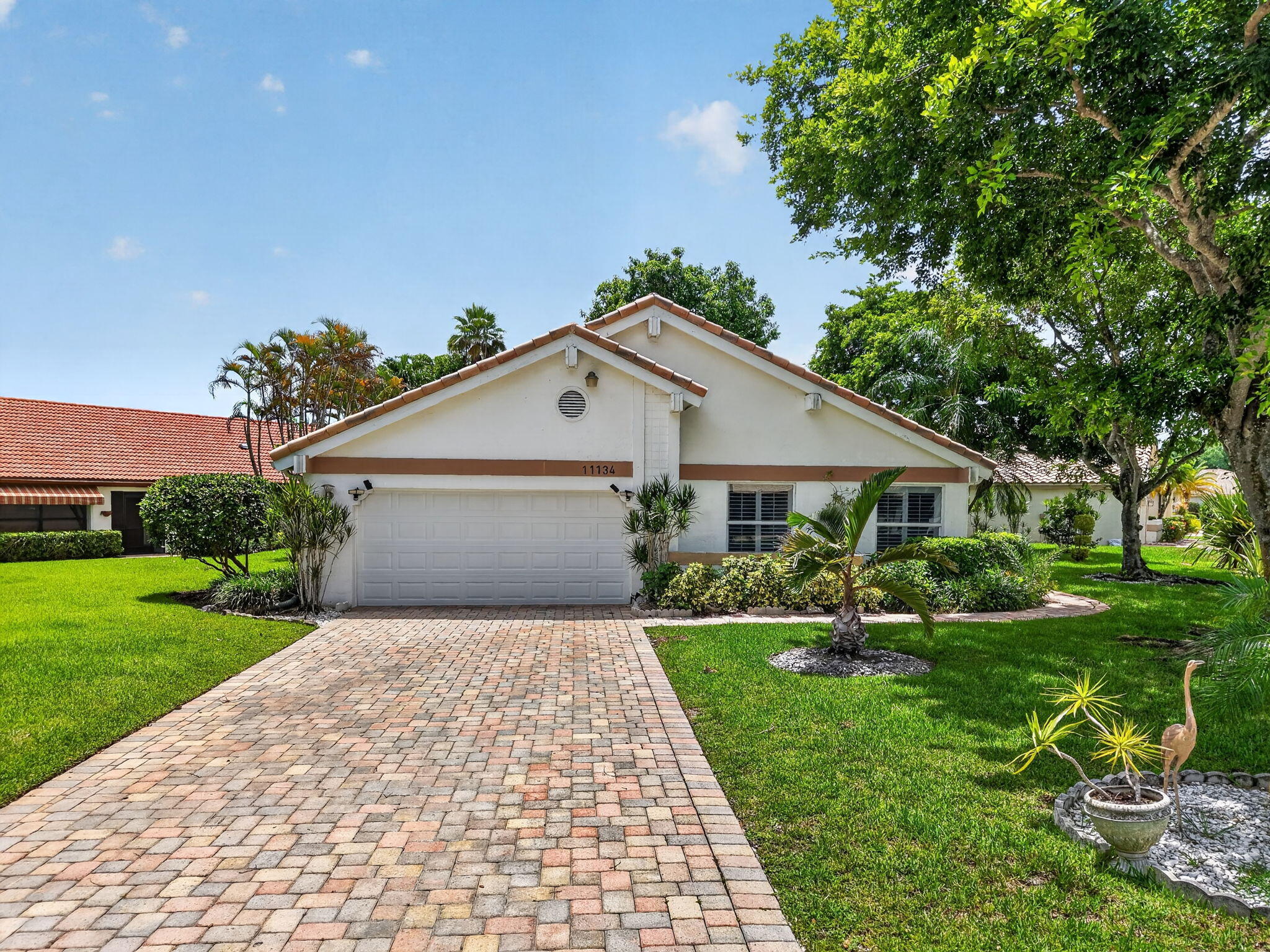 Boca Woods Country Club Home on Oversized Corner Lot. Rare opportunity in gated BWCC on an oversized quarter acre corner lot with a peaceful water view. This home features a flexible den with wet bar hookup, ideal as a 3rd bedroom, home office, or entertainment space. Enjoy a large screened patio, oversized paver driveway, and impact windows and sliders. Amenities include two eighteen-hole golf courses, tennis, pickleball, a fitness center, and a recently renovated clubhouse. Community dues include Hotwire cable television, high-speed internet, and ADT security monitoring.  Being sold as-is and priced to reflect condition — a fantastic opportunity to renovate and build equity in a community where updated homes sell well above this list price. Membership required. Schedule today!
