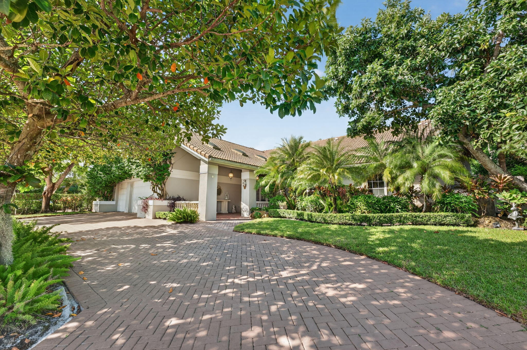 Tropical Oasis awaits! Welcome to your beautiful updated 4 bedroom 4 bath home in Boca Grove Golf Club . This home sits on a lush 1/3 acre lot offering stunning light-filled living space with soaring ceilings overlooking the 11th fairway, a circular driveway and a 3 car garage with 2 electric charging stations.  Entertain in this 3554 sq ft home with large open living areas and beautiful new porcelain floors throughout. Enjoy a formal dining area, living room, sunroom and beautifully remodeled kitchen.  The primary suite offers volume ceiling with 2 separate beautifully remodeled bathrooms with steam shower, bath, sauna, and outfitted closets.  This home will have you enjoying the view through your French doors overlooking your serene, landscaped backyard. Step outside to your private oasis with outdoor dining, lounge areas, and spacious lanai where you can sit and enjoy your golf course view, sparkling pool and many organic trees including mango, banana, lychee and avocado.  Boca Grove is known for its world-class 18 hole golf course designed by Jim Fazio, tennis center, pickleball, padel, state of art fitness center, dining, clubhouse, and resort style pool.  Short walk to houses of worship.