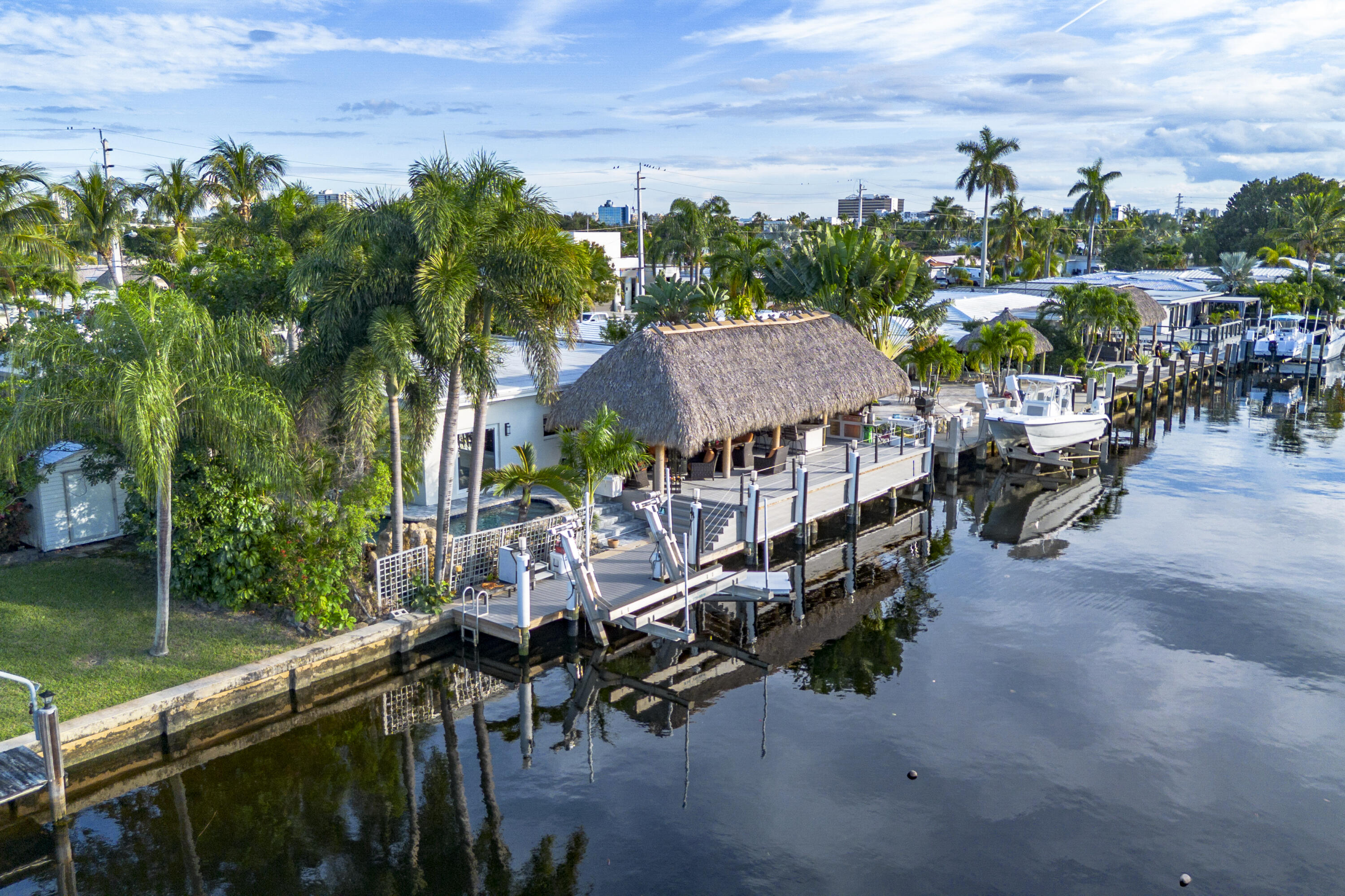 PARADISE, PERFECTED.
This extraordinary waterfront estate is a rare convergence of refined design, uncompromising craftsmanship, and effortless coastal living. Upon arrival, the home captivates immediately—an expansive, newly reimagined open-concept interior frames uninterrupted views of the deep-water canal, drawing the eye straight through to your private 75' dock and brand-new 15K LB boat lift.
Completely taken down to the studs and rebuilt, this residence offers peace of mind and modern luxury throughout. A new 38' steel support beam allows for soaring ceilings, while impact-rated doors and windows, new walls, electrical, plumbing, and natural gas lines reflect a level of renovation rarely found. The gourmet kitchen is a showpiece—high-end stainless appliances, professional hood range, soft-close custom cabinetry with pull-out shelving, and exquisite quartzite countertopsdesigned equally for entertaining and everyday elegance. A flexible bonus space seamlessly transitions between a private theater and a fifth guest bedroom, featuring a custom-designed Murphy bed with integrated shelving and storageperfect for hosting in style.
Step outside and experience a resort-caliber backyard oasis that defines Florida luxury living. A spectacular newly constructed tiki pavilion (2024)soaring 20 feet high and spanning over 1,050 square feet of covered entertaining spacesets the stage for unforgettable gatherings. No detail was overlooked: rope-wrapped columns, ambient accent lighting, and a fully equipped commercial-grade summer kitchen featuring dual refrigerators, beverage cooler, ice maker, Twin Eagle grill, flat grill, rotisserie, side-by-side burners, prep sink, storage drawers, and a dedicated condiment station.
The expansive quartzite-topped bar comfortably seats six, complemented by oversized fans, multiple seating areas, recliners, and dual 100" TVs, creating the ultimate setting for entertaining or relaxing waterside. Trex decking and modernized dock railings (2024) preserve unobstructed water views while enhancing durability and style.
Surrounded by lush, professionally landscaped grounds with custom lighting, the lagoon-style saltwater pool with rock waterfall offers year-round enjoyment, enhanced by a new electric pool heater (2024). Dock lighting above and below the water ensures effortless nighttime navigation and fish visibility.
Additional features include a 15kW whole-house generator, tankless hot water heater, and fully permitted upgrades completed by licensed local contractorsdelivering both luxury and reliability.
All of this is perfectly positioned just 15 minutes to the inlet, offering seamless access to open water and world-class boating.
This is not just a homeit's a waterfront lifestyle without compromise.