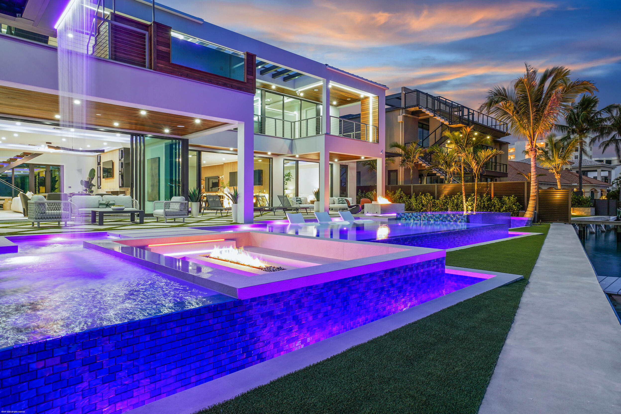 Built by award-winning High Tide Waterfront Properties on Jupiter's iconic Bahamian-blue Intracoastal, this brand-new residence delivers a true sense of arrival with standout design and thoughtful execution throughout. From the moment you enter, your eye is drawn through the home to the beautiful blue water views beyond, setting the tone for the living experience inside. Expansive living spaces are finished with high-end materials and meticulous attention to detail. High Tide is known for thoughtfully building homes that make the experience of living in them unmatched, and this property is no exception. Designed for entertaining, the backyard features multiple fire pits, a fully equipped outdoor kitchen, a waterfall feature, and inviting spaces to gather and relax along the water, creating an atmosphere that draws friends and family in. The chef's kitchen is outfitted with top-of-the-line appliances and designed to seamlessly connect to the home's main living and entertaining areas, including a club room ideal for hosting. Both first and second floor primary suites offer flexibility and privacy, while the second-floor balcony showcases a hot tub with sweeping Intracoastal views.  Complete with a 32,000-pound boat lift and direct ocean access with no fixed bridges, this property delivers the ultimate Jupiter waterfront lifestyle. There is simply too much to capture in words—this is a home that must be experienced in person to fully appreciate.