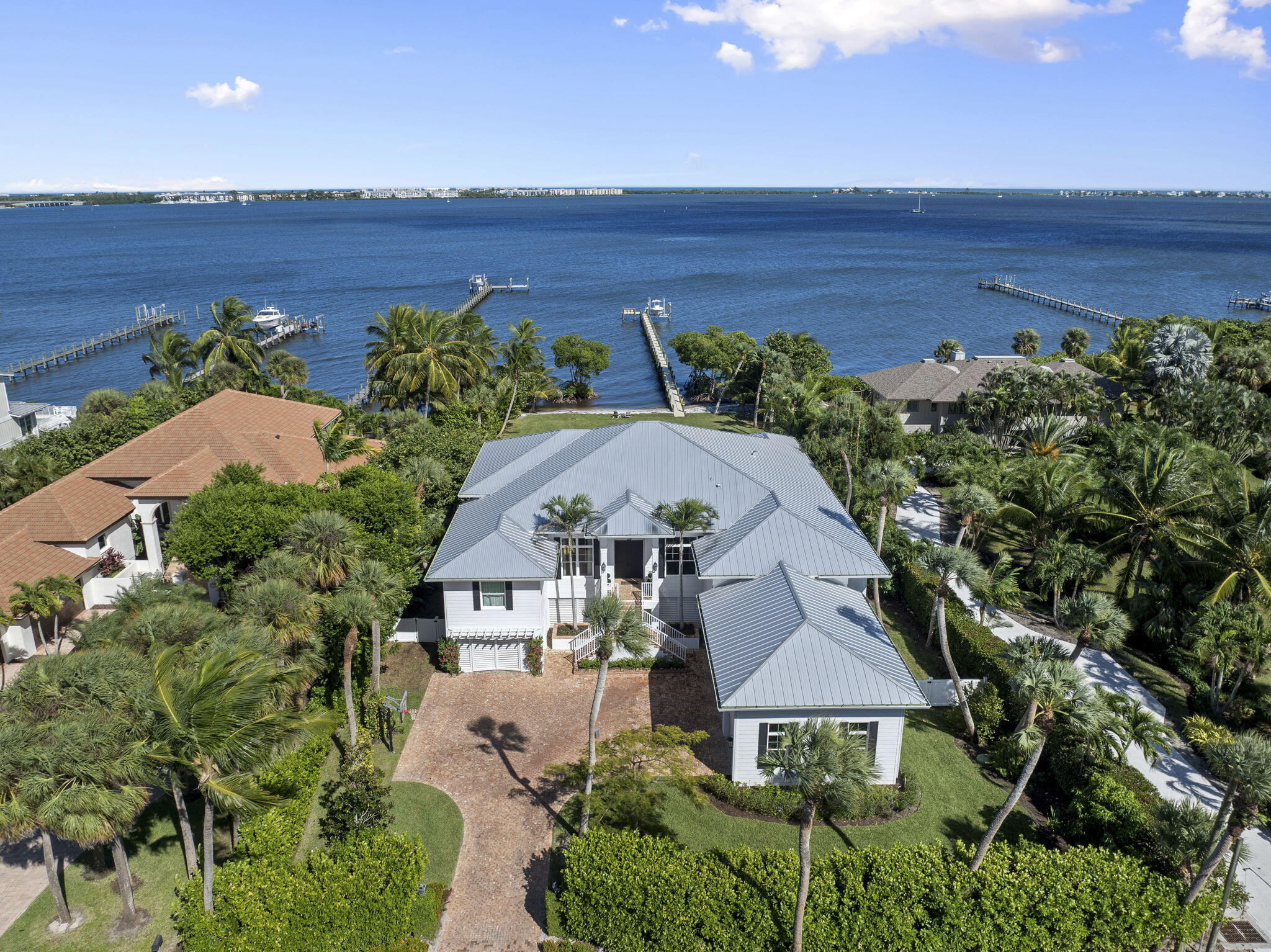 Gorgeous new build, wide-waterfront home on one of South Sewall's Point's most historic parcels. Built in 2020 on 3/4 acre, this classic modern property offers 4085 sf under air, pool, large backyard, sweeping wide water views and a white sand beach. 4 bd./4.5 bath with an office, bonus game room, and three car garage. Features include wide plank wood flooring, Sub Zero and Wolf appliances, elevator, generator, impact windows and doors, spacious kitchen, large island, and state-of-the-art security/surveillance system. Outdoor living includes a covered lanai, saltwater heated pool/spa, putting green, plans for outside addition and cabana, and beautiful eastern views of lagoon & Hutchinson Island. Private new dock, 16000 pound lift and completed sewer connection. Must see rare opportunity. Set on one of Sewall's Point's most notable and beautiful wide waterfront sites, this property blends a meaningful past with coastal luxury, perfect for entertaining, relaxing, or watching the sunrise. Once home to the original 1800s Harmer residence with rumored ties to Al Capone, the property now features a custom, no-expense-spared 2020-built home offering refined finishes, clean architectural lines, and exceptional indoor-outdoor living.
Bright, open spaces with high ceilings, wide-plank wood flooring, and expansive windows capture sweeping eastern views toward Hutchinson Island, the House of Refuge, the Hutchinson Island Bridge, Bird Island, and the Intracoastal Waterway.
The home offers 4,085 square feet under air with four bedrooms, four-and-a-half bathrooms, a library, a bonus game room, and a three-car garage with generous storage and workout configuration. The chef's kitchen includes a Sub Zero refrigerator and Wolf gas appliances, a large center island with storage, custom cabinetry, and seamless flow into the living and dining areas. The living room includes a cozy Chicago brick gas fireplace surrounded by custom built-in bookshelves and mantle. Multiple sliders open to a spacious covered lanai for outdoor lounging or hosting. The home features an oversized 40x20 saltwater pool with dual gas and electric heating capabilities and electronically app-controlled lighting and heating systems.
The outdoor dining and lounging areas include a putting green, manicured yet lush landscaping, uplighting, mature palm trees, and an herb garden. The vast and substantial backyard is perfect for outdoor sports or is buildable with included plans for future cabana expansion. The front yard includes an 11-foot mature privacy hedge, a mango tree, a Poinciana tree, and a Magnolia tree.
A private dock with a 16,000-pound lift and a dredged navigable slip provides direct access to the Intracoastal, Boy Scout Island, the Sandbar, Sailfish Point, Downtown Stuart, and Jupiter. The dock is constructed with WearDeck composite decking, upgraded lighting, and 10-inch pilings for added stability, with composite materials that offer exceptional resistance to heat and long-term durability.
The wide, white sand beach is met by the idyllic waters of the Indian River Lagoon, providing opportunities for dolphin, manatee, and various wildlife sightings. Additional features include an elevator, full house generator, impact windows and doors, and a fully completed sewer connection with new Sewall's Point Road enhancements for a high and dry elevation. This residence combines custom craftsmanship, historic significance, and a premier waterfront lifestyle in one of the most desirable communities on the Treasure Coast. Wonderful for children or retirees, this rare opportunity will not last.