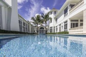 Extremely rare opportunity in the Estate Section of Delray Beach. This oceanfront residence adorns the Estate Section of Delray Beach’s Coastline. The completely gated and private estate is nestled off A1A just south of Atlantic Avenue’s shops and restaurants and an easy and scenic drive to Palm Beach and Boca Raton. With 100 feet of direct ocean frontage and over 408 feet of depth, the nearly one acre parcel is the perfect setting for this resort-style residence boasting over 12,000 square feet. The private gated main entry and decorative motorcourt lead to the majestic estate and manicured grounds. A Coquina stone arched entryway complete with iron gate and custom wood and glass door unveil the opulent living room with cathedral wood beamed ceilings; stone columns, millwork and fireplace and is flanked with numerous windows providing an abundance of natural light and views of the pool, spa and ocean. The formal dining room is complete with a full-service catering kitchen and butler's pantry. Enjoy the home theatre room and wood paneled library and game room. The first floor master suite is complete with coffered ceilings, fireplace, office, his-and-her baths, and a private seaside loggia. There are six additional guest rooms including a second master suite with balcony, full bath, closet fireplace and morning bar, as well as a third level observation area displaying the endless ocean views. The resort-style grounds with manicured lawns and sprawling green spaces are the perfect setting for the expansive seaside pool and spa complete with separate cabana bath. Entertaining is easy with the Coquina terraces, covered loggia and outdoor dining area. Recent improvements include brand new air conditioners, several renovated bathrooms, and new exterior and interior paint. Exceptional features include marble and hardwood floors throughout, central lighting system, electric shutters, numerous fireplaces, elevator, ground floor master suite, full service bar off of the living room, additional game room, full service laundry room, central vacuum system, two bedrooms with separate entrances that can serve as staff quarters, custom landscape, incredible trim and woodwork throughout, and a fantastic deep oceanfront lot. Enjoy the opulent architecture and luxury lifestyle in this private oceanfront estate.