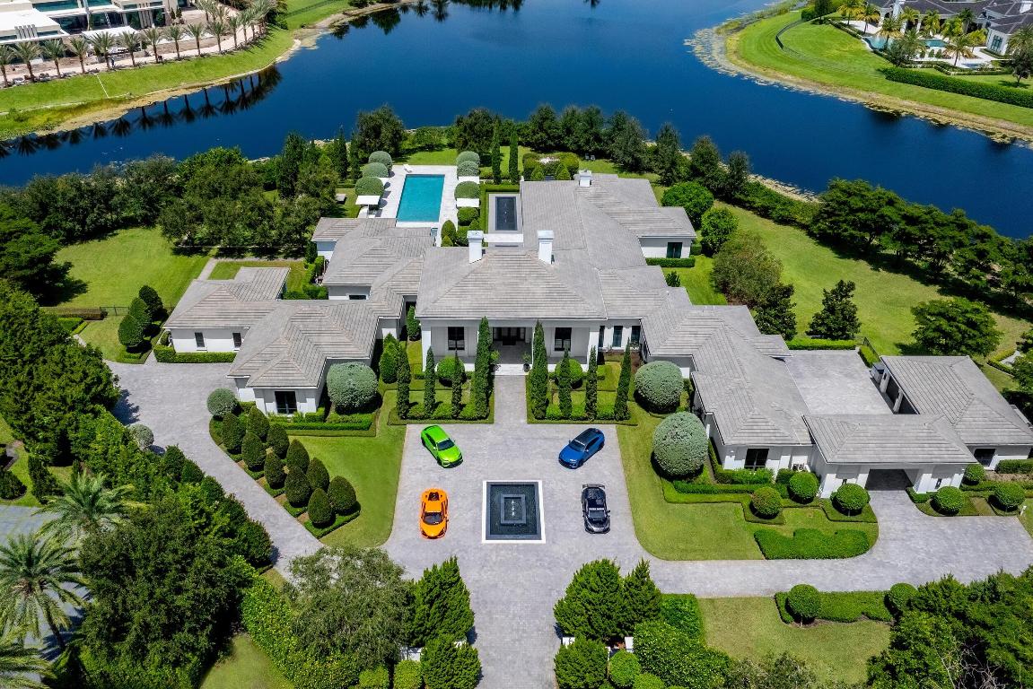 Villa Ananda is a contemporary masterpiece that embodies serenity and sophistication within Stone Creek Ranch in Delray Beach - South Florida's premier enclave hailed as the ''Billionaires' Row.'' Featured on CNBC, The Wall Street Journal, and in leading global design magazines, this estate is a rare fusion of architectural brilliance, natural beauty, and adrenaline-fueled elegance, with an automotive pedigree worthy of a champion driver. The result is a definitive statement in refined luxury living. Reminiscent of the French Riviera, Villa Ananda is sited behind private gates on 2.5 lush acres with sweeping lakefront vistas and an extraordinary 660 feet of waterfront. This single-story compound spans approximately 17,031 total square feet, with 11,457 square feet under air. Inspired by the tranquil elegance of iconic Aman Resorts, the estate embodies the essence of a private retreat - offering a rare balance of serenity, privacy, and security.
Outdoors, the property transforms into a resort experience, with gardens designed by renowned landscape architect Krent Wieland. Italian cypress, roses, bougainvillea, and Japanese blueberry trees frame the grounds as living art - creating vibrant vistas by day and a cinematic glow by night with curated lighting and the gentle sound of fountains. A covered lanai with fireplace, retractable screens, and a built-in grill extends the interiors seamlessly into the open air, while a bougainvillea-draped pergola and fire pit invite intimate gatherings under the stars.
Car enthusiasts will prize the rarity of nine air-conditioned garage bays - expandable with lifts to accommodate up to 18 vehicles - an amenity created for the passion of a Lamborghini Super Trofeo race-car driver. This extraordinary feature makes the estate as functional as it is breathtaking, complete with an arrival area designed to handle race car carriers. With the scale of the property, a true aficionado could expand even further, creating space for a collection that extends well beyond 18 cars.
Inside, every element reflects intentional world-class craftsmanship and design. Envisioned by Inson Dubois Wood Interiors, the spaces are dressed in soft shades of gray and white, accented with artisanal finishes that transform each room into a work of art. Furnishings - offered separately - include bespoke pieces from the Christian Liaigre Collection, adding an additional layer of refinement. European white oak floors provide a natural yet sophisticated foundation, while custom millwork and wall treatments blend seamlessly with lighting designed around Selenite crystal. Celebrated for promoting clarity and positive energy, the crystal infuses the interiors with both beauty and a restorative ambiance.
The kitchen stands as a showcase of style and function, anchored by a dramatic Calacatta Crema marble island that invites gathering, dining, and entertaining. Equipped with Sub-Zero refrigeration, dual Wolf ovens, and Bosch dishwashers, it delivers state-of-the-art performance with striking visual appeal. Beyond, a succession of elegantly scaled rooms unfolds with effortless continuity, each designed to capture abundant natural light and frame sweeping views of the water.
The primary suite unfolds as a private wing of the estate - an exclusive sanctuary designed for ultimate comfort and versatility. It features the main bedroom, a secondary bedroom, a dedicated office, and dual baths and closets, creating a retreat that is both indulgent and highly functional. More than a suite, it is a self-contained domain within the residence, offering complete privacy and refinement. Boutique-style closets have been custom designed with precision, while spa-inspired baths provide moments of retreat and restoration. In addition to the primary wing, six additional bedroom suites each offer their own distinct sense of luxury, complemented by seven full bathrooms and three powder rooms finished to the highest standard.
Villa Ananda integrates technology and security with seamless sophistication, delivering both comfort and peace of mind. Crestron home automation and a Sonos sound system provide effortless control, while impact windows, a full-house generator, lightning protection, and advanced UV water and air purification ensure resilience and well-being. For leisure, a club room with a 150-inch projection screen brings the cinematic experience home. 
Completed in 2018 and extensively reimagined in 2019, Villa Ananda was expanded with a dedicated guest wing, enhanced living areas, and a full redesign of its landscaping, pool, and finishes. The result is a residence that feels entirely new, yet carries an enduring sense of tranquility and permanence.
Stone Creek Ranch itself is synonymous with prestige, offering residents the assurance of a 24-hour manned gate and armed roving security. Tucked away on a quiet cul-de-sac, Villa Ananda enjoys complete privacy while remaining just moments from the education, cultural and lifestyle destinations of South Florida. Top private and public schools are minutes away. Downtown Boca Raton lies only 12 miles away, Delray Beach's vibrant Atlantic Avenue is 12.5 miles, and Palm Beach's iconic Worth Avenue is just 27 miles to the north.
Every detail of Villa Ananda has been curated to embody harmony, elegance, and distinction. More than a residence, it is an experience, a sanctuary, and a legacy estate that stands as the pinnacle of South Florida living.