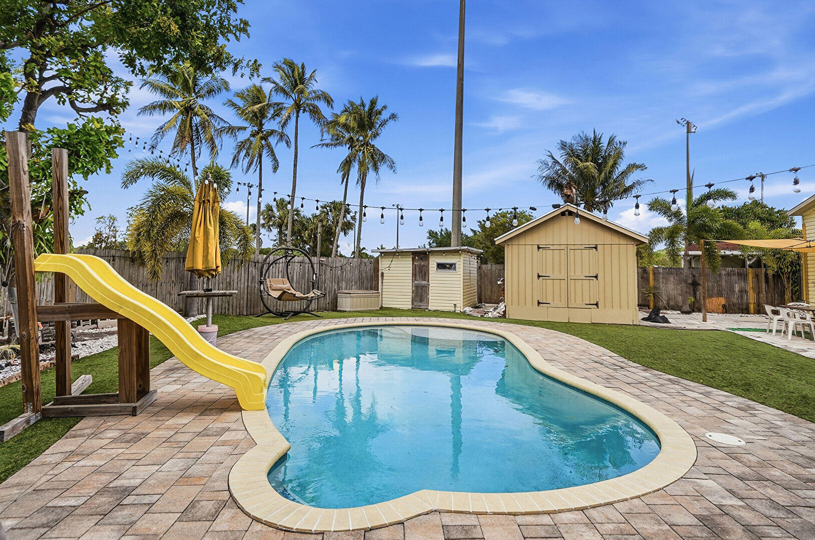 You own the Land with your 2018 Manufactured Home. Convert ADU to in law suite, build your dream home or just enjoy the standout home that already exists.  The oversized corner lot offers privacy, space, and exceptional outdoor living. Relax in your backyard oasis with an inground pool, 2 tiki huts, and a fully fenced yard. Inside features an open layout with spa-style shower, a jacuzzi tub, new floors, custom countertops, and inviting living areas. Includes 2 sheds for added storage, one brand new. Enjoy backyard access to Patrick J. Meli Park. Community offers pool, playground, tennis, pickleball, and clubhouse. Quiet location near beaches, I-95, Hard Rock, Fort Lauderdale Airport, restaurants, shopping, and Tri-Rail.
