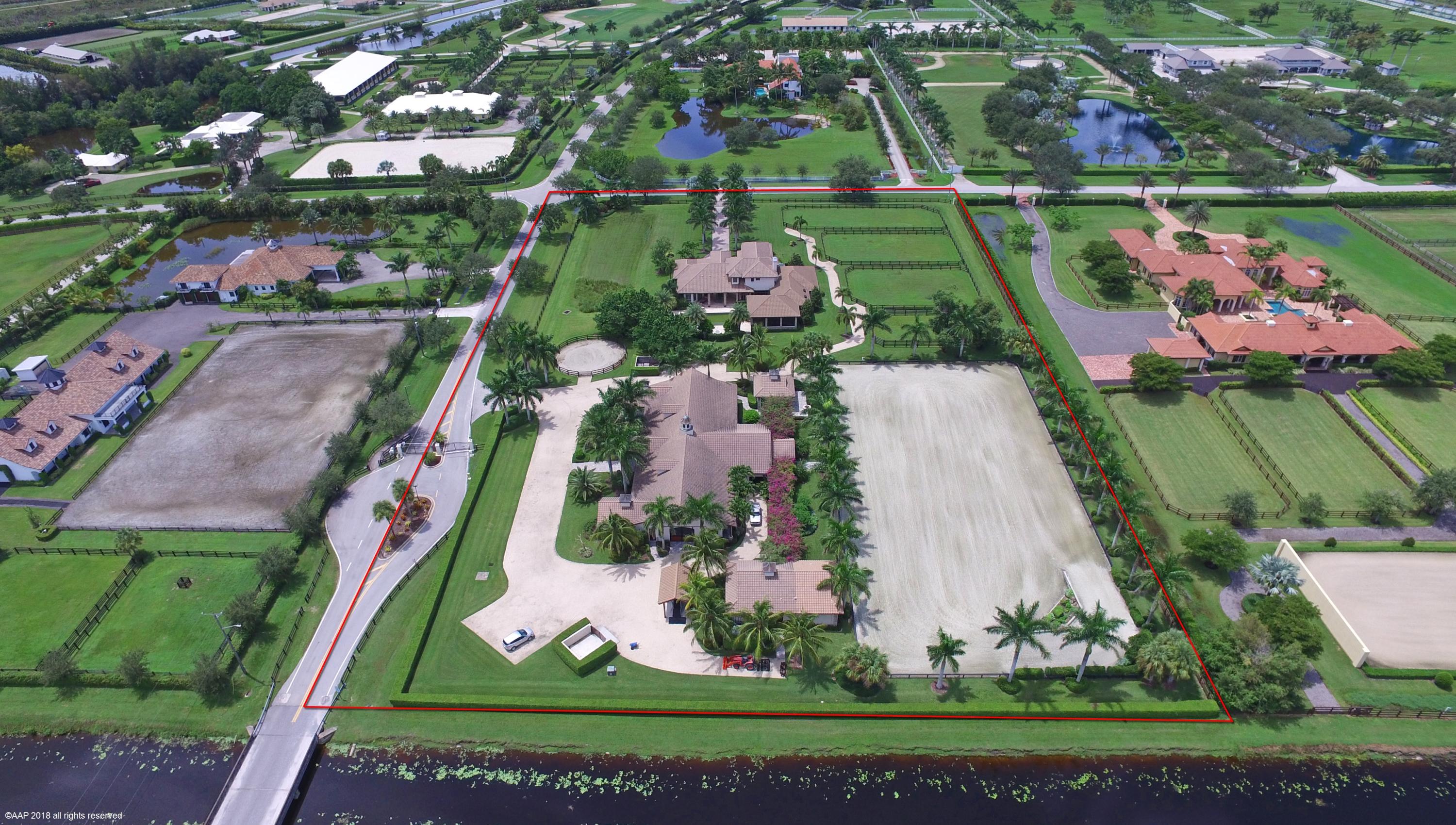 This exquisite Palm Beach Point property is an equestrian's dream! The main house has 6 bedrooms (+ office), 5 full + 2-1/2 baths and beautiful marble & hard wood floors, volume ceilings, French doors & crown molding throughout. The kitchen has stainless steel Thermador DOUBLE wall ovens, refrigerator & dishwasher and a GE stove & microwave. There is a double sided gas fireplace in the family room & media room, which overlooks out to the covered extremely large Summer kitchen. There is a beautiful outdoor bar with tongue & groove ceiling, granite counters, stainless steel double door refrigerator, wine cooler, ice maker, dishwasher, gas grill & a Big Green Egg. The covered patio has electric roll down screens looking out to the pool/patio area with a waterfall extending from the hot tub. There is also a fire pit with sitting area and outdoor shower. The property has a gorgeous 3 bedroom, 2 bath guest house (built in 2017) that comes complete with a full kitchen and washer/dryer. The 12-stall barn has fly spray system, fans in each stall, 4 wash rack cross ties, air conditioned tack room, laundry room and half bathroom. There is a large feed room and storage room with garage door. The barn also has a oversized grooms apartment, complete with a living area, full kitchen and double bedroom. The fully irrigated 130'x250' riding arena has all weather footing and a beautiful air conditioned viewing lounge with bar so that you can see all the action! Property also has a Reverse Osmosis System, 1,000 gallon propane tank, separate barn driveway, covered tread mill area, double manure bins, 4 paddocks and a lunge pen. This is an exceptional property and an absolute MUST SEE!!