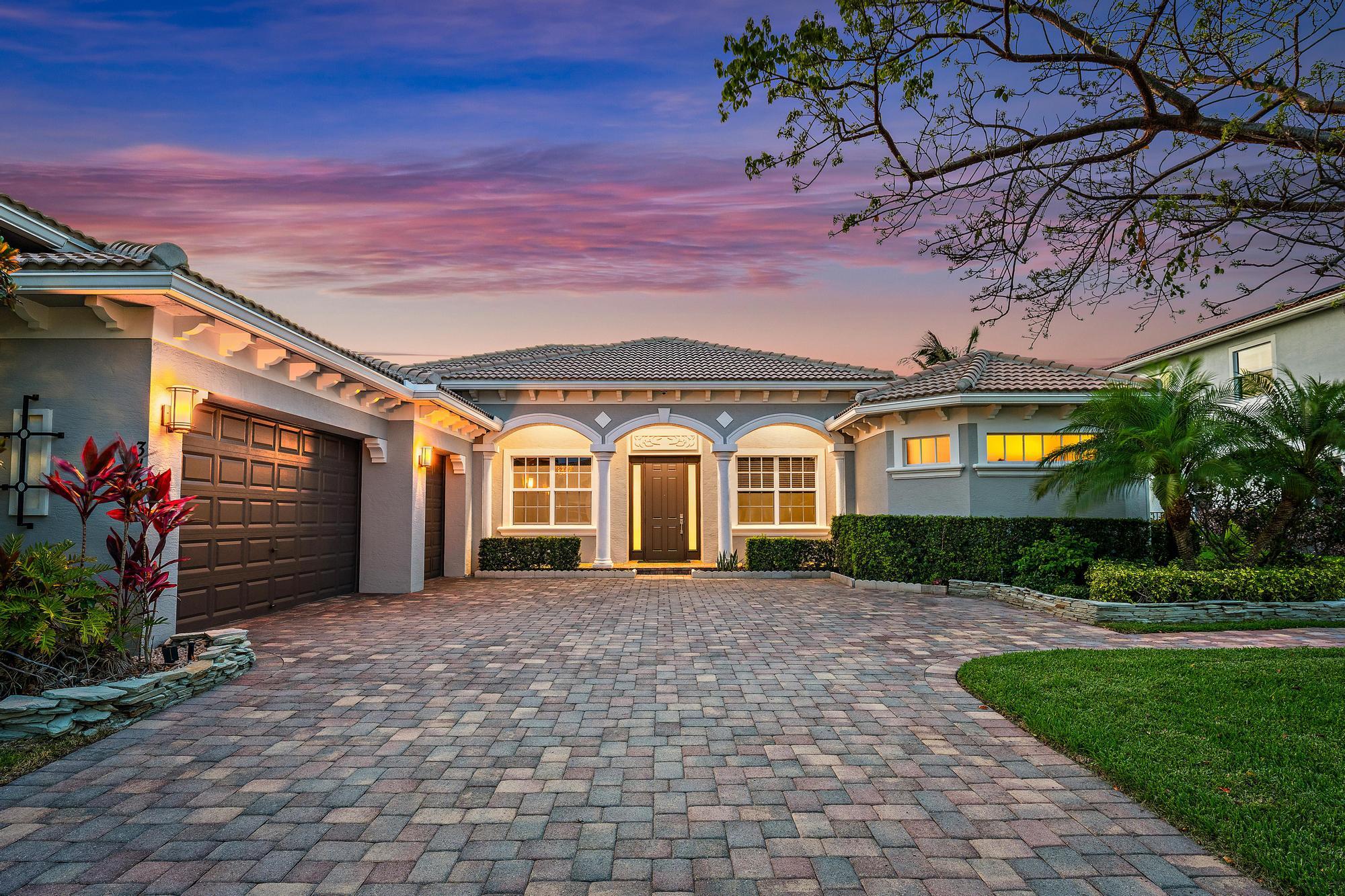 Luxury living awaits in this rare-to-market Stockton model, nestled within the gated, family-friendly community of Rialto. Built in 2015, this exceptional single-level residence delivers 3,046 square feet of masterfully designed living space across four bedrooms, three baths, a den, and a three-car garage. An extra-long driveway offers generous guest parking, while the thoughtfully split floor plan ensures the primary suite remains a true private sanctuary — quietly removed from the main living areas and guest accommodations.  From the moment you step through the foyer, the home makes its intentions clear. Clean architectural lines, a soft neutral palette, and elevated finishes establish a tone that is at once warm and refined. Porcelain tile flows seamlessly through the main living spaces, transitioning to rich wood flooring in every bedroom, while smooth-finish walls, fresh paint, and crown molding throughout the living areas and primary suite lend a polished, unhurried elegance to every room.  The kitchen is a genuine chef's retreat — appointed with granite countertops, rich espresso cabinetry, stainless steel appliances, double wall ovens, dual EdgeStar wine coolers, and a newer refrigerator. Open to the great room, this space was designed equally for quiet mornings and spirited entertaining, with sweeping views of the pool, spa, and shimmering lake beyond serving as a constant, breathtaking backdrop. Just off the kitchen, a private guest bedroom and bath with direct pool and patio access creates an ideal suite for in-laws or extended visitors. Two additional guest suites, each with generous walk-in closets, share a well-appointed guest bath.  The primary suite is a study in understated luxury. Coffered ceilings, wood flooring, and crown molding set the stage for a beautifully appointed bath complete with dual vanities, a soaking tub, and a walk-around shower — a true escape at the end of the day. Every closet throughout the home, including the pantry, has been upgraded with custom built-ins from The Container Store, where thoughtful organization meets impeccable style.  The home's infrastructure is equally impressive. Hurricane impact windows and doors protect every opening, while a whole-house generator, water softener system, 1000lb propane tank, mosquito misting system around entire backyard, UV lights on the AC, and a camera system ensure comfort, security, and peace of mind through every season.  Step outside and the luxurious lifestyle continues. The oversized covered lanai opens to a spectacular outdoor retreat, where herringbone travertine marble decking frames a heated saltwater pool, spa, and cascading waterfall. A spacious tiki hut with a full summer kitchen, sauna and wet bar anchors the outdoor entertaining space, while an electric awning and roll-down screen provide effortless shade from the Florida sun. Lush, upgraded landscaping wraps the property in privacy and comes alive after dusk with landscape lighting and outdoor speakers — making the backyard as compelling by night as it is by day.  With tranquil lake views, expansive outdoor living, and room for children and pets to roam freely, this home represents the very best of Florida living in one of Rialto's most coveted floor plans. Opportunities like this simply do not come around often.  Rialto is a premier gated community with access to A-rated schools, and a beautiful nature preserve. The HOA maintains both the front and back lawns as part of the dues, allowing for a low-maintenance lifestyle. Residents enjoy an impressive clubhouse with a fitness center, a children's splash park, a resort-style pool and jacuzzi, multiple playgrounds, basketball courts, two tennis courts, and scenic walking and jogging trails. The active social committee regularly organizes events for all ages. Just across the street, Jupiter Community Park offers a variety of sports programs for both kids and adults.    Ideally located in the heart of Jupiter, this home is just minutes from stunning beaches, fine dining, and upscale shopping. Convenient highway access via I-95 and the Turnpike makes travel easy, with Palm Beach International Airport only a short drive away.