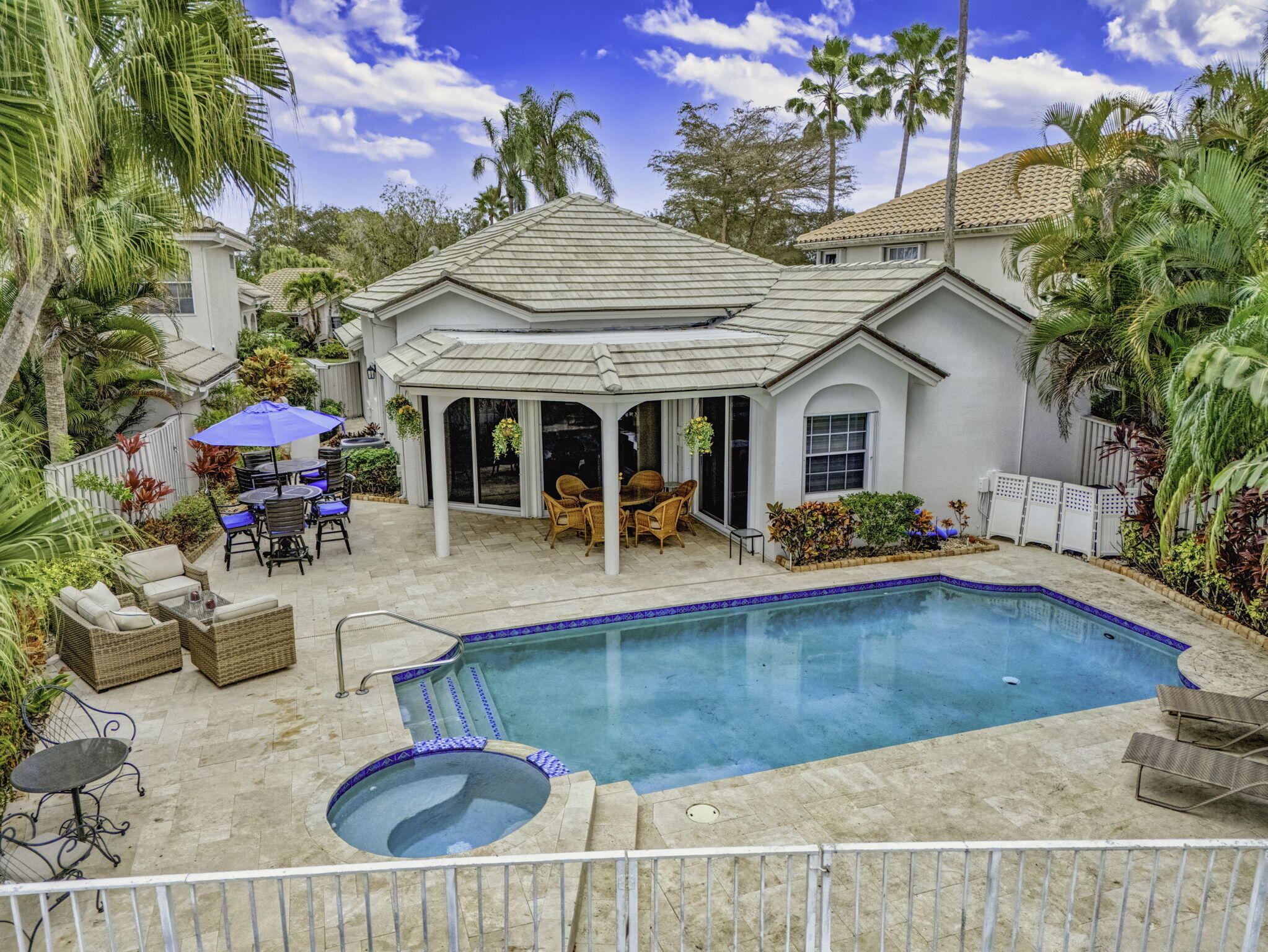PGA National living at its finest. Upon entry, you're welcomed by an open floorplan, soaring ceilings, and beautiful custom built-ins that create an inviting yet refined atmosphere. This thoughtfully designed home features three bedrooms, two bathrooms, custom window treatments, a formal dining area, soft-closing kitchen cabinetry, travertine flooring in the main living areas. Step outside to your private backyard retreat--fully fenced and designed for entertaining. Enjoy a built-in Lynx BBQ grill, heated pool and spa, lush tropical landscaping, and elegant travertine pool decking. Take in tranquil water views and stunning sunset skies from your own outdoor oasis. Additional highlights include accordion shutters, central vacuum, and the comfort of living
