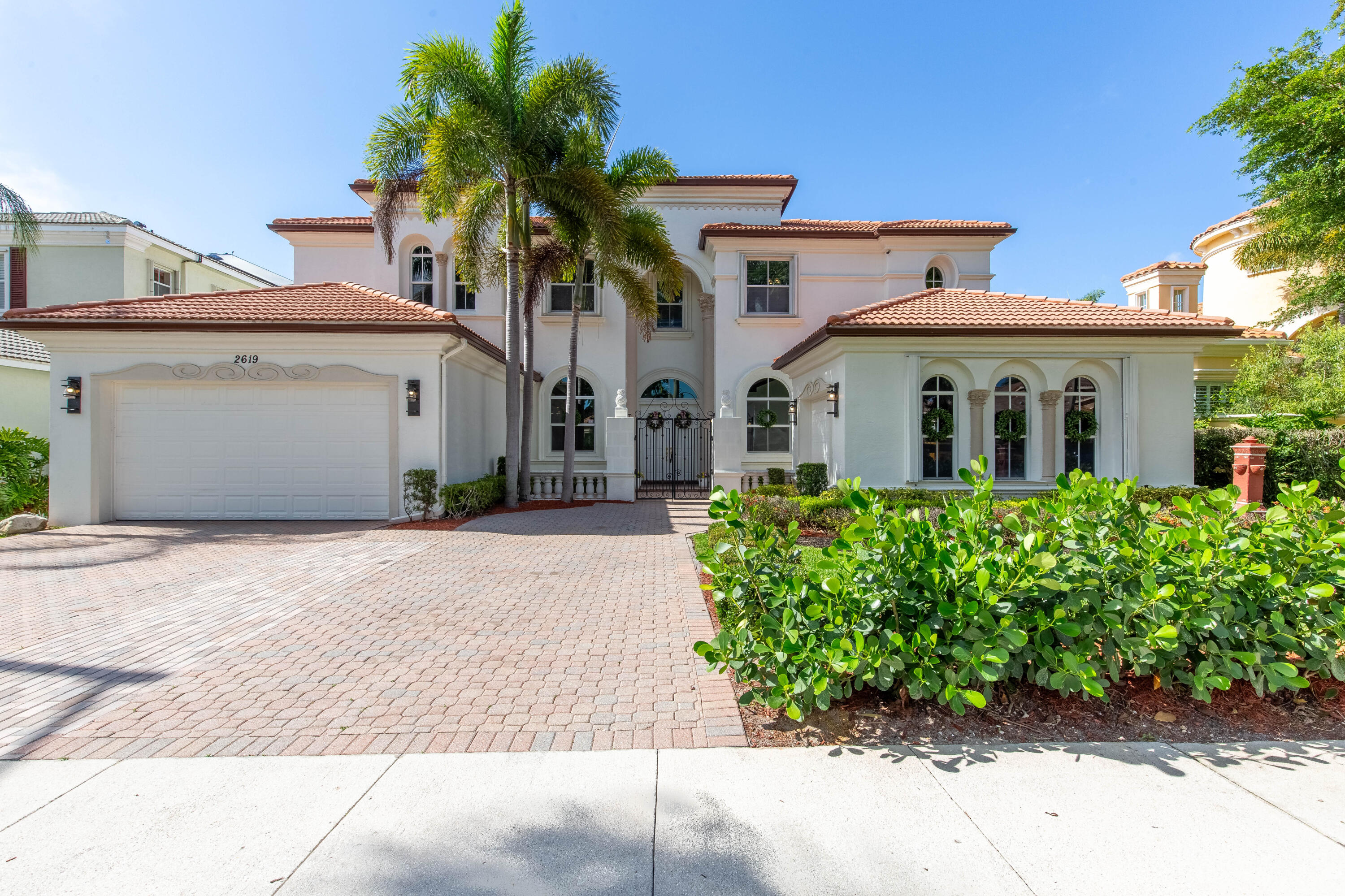 Welcome to sophisticated coastal luxury at 2619 Treanor Terrace, an expansive 5,600 square feet of refined living under air, totaling nearly 7,000 square feet with additional outdoor spaces. This meticulously appointed estate presents an architectural masterpiece designed for the discerning buyer. Upon entry, you're greeted by a soaring picture window framing the elegance within, complemented by dual staircases that define the home's grand foyer. The main level showcases exceptional flow across multiple entertaining spaces: two generous living rooms, a dedicated library/media room, and a gourmet kitchen featuring custom cabinetry and granite countertops. Two full bedroom suites with en suite bathrooms anchor the ground floor.  A powder room and cabana bath serving the pool area. The crowning jewel awaits upstairs: an expansive master bedroom with private balcony overlooking the tranquil canal, a generous walk-in closet, and a spa-like en suite bath appointed with travertine flooring. Additional guest bedrooms with en suite bathrooms complete the upper level. Outside, resort-style living centers on a breathtaking pool featuring a cascading waterfall, ideal for entertaining and relaxation. A three-car garage with Tesla charger infrastructure completes this luxury residence, blending modern convenience with timeless elegance. Nestled in the prestigious Olympia master-planned community, this home offers unparalleled lifestyle amenities across 832 acres. Enjoy a resort-style lagoon pool, state-of-the-art fitness center, tennis and basketball courts, island spa, walking trails, and a grand Mediterranean clubhouse. The community features 24/7 guarded security with multiple gated entrances, creating an exclusive, safe sanctuary. Wellington's education excellence defines this address. Equestrian Trails Elementary School, Emerald Cove Middle School, and Palm Beach Central High School provides advanced placement and specialized programs. This is Olympia—where luxury, security, and opportunity converge.