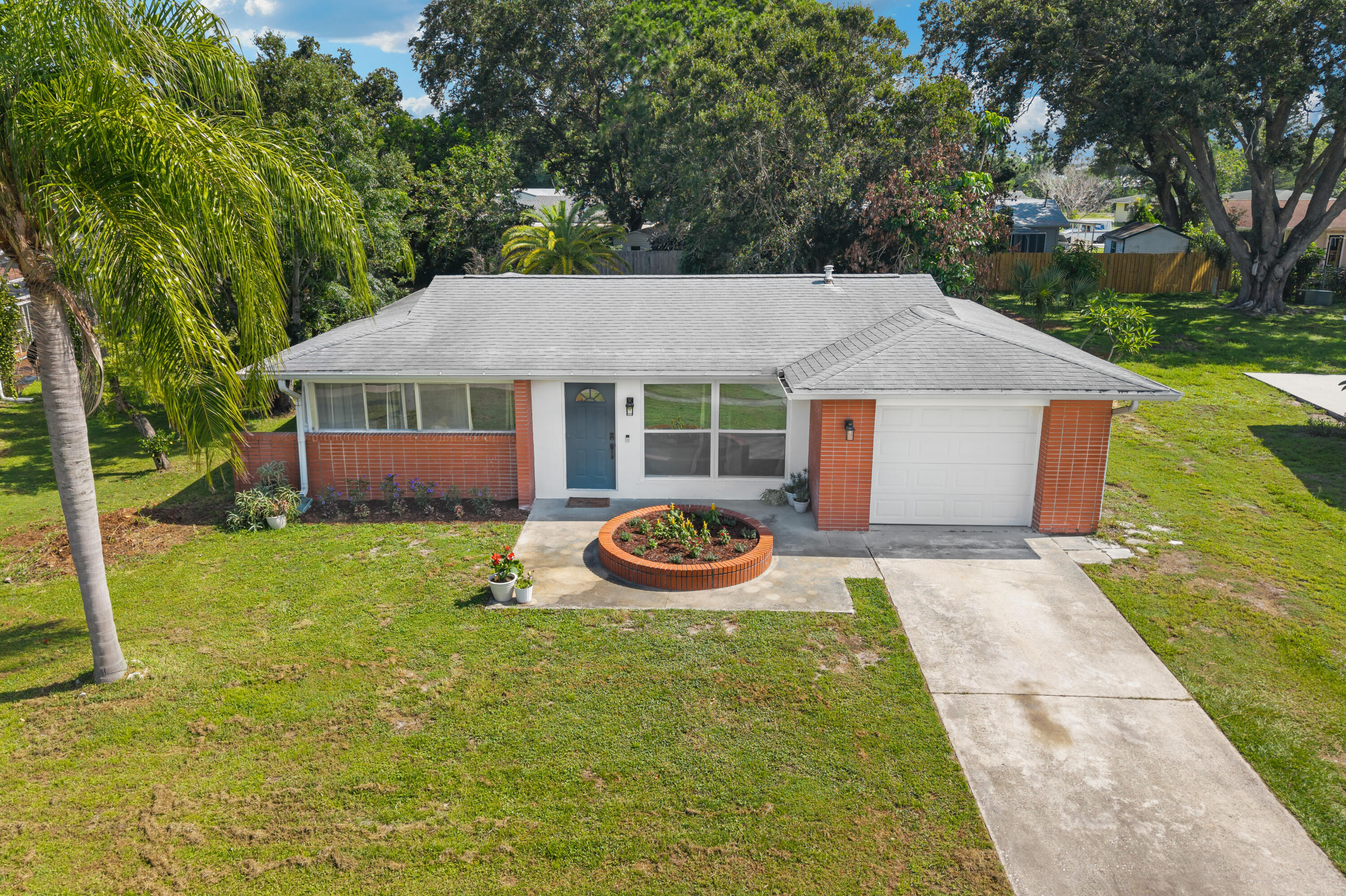 Modernized, Move-In Ready Gem on a Huge Quarter-Acre Lot!  Welcome home to this stunning, fully updated single-family ranch that perfectly balances modern interior luxury with an unbeatable, central Port Saint Lucie location. Minutes from top-rated schools, premier shopping centers, hospitals, and dining, this home offers the ultimate lifestyle convenience. Step inside to a light-filled, open-concept floor plan adorned with beautiful, low-maintenance wood laminate flooring - completely carpet-free! Gorgeous, updated kitchen, fully equipped with premium stainless steel appliances, sleek grey shaker cabinetry, matte black hardware, and crisp white countertops. The seamless flow leads into a spacious living area and an inviting dining space, making it perfect for entertaining.  Extend your living space outdoors into the generous, fully enclosed sunroom - an ideal spot for your morning coffee or evening relaxation. The sunroom opens up to a massive, lush backyard dotted with mature palms, offering a private tropical oasis with endless space for pets, play, or a future pool. Complete with an attached 1-car garage, a concrete driveway, and delightful front brick accent curb appeal, this turn-key property is ready for its next chapter. Schedule your tour today!