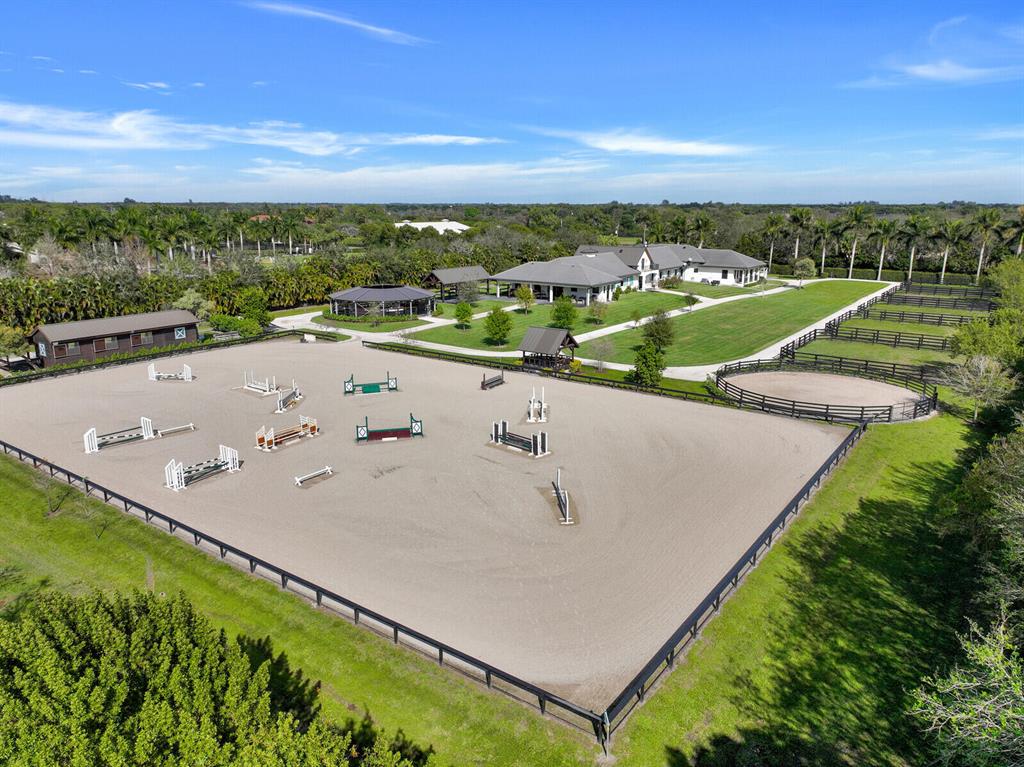 An equestrian paradise located in Palm Beach Point East! Situated on 5 beautifully manicured acres this stable features 2 barns totaling 20 stalls. Center aisle 16 stall main barn with custom cedar wood tack room & lounge. Newly constructed 6 horse covered walker, 8 covered grooming stalls, and approx. 2000 ft. circular bridle path. The property also features 2 apartments. The first is 2 beds, 2 baths complete with cathedral ceilings and luxury finishes. Second apartment is 2 beds, 1 bath with a full kitchen and large living space. A covered viewing area overlooks a 220' x 140' irrigated GGT all-weather arena. This property is complete with 5 paddocks and a 60ft round pen w/ all-weather footing. Don't miss the opportunity to own this thoughtfully designed stable perfect for any equestrian.