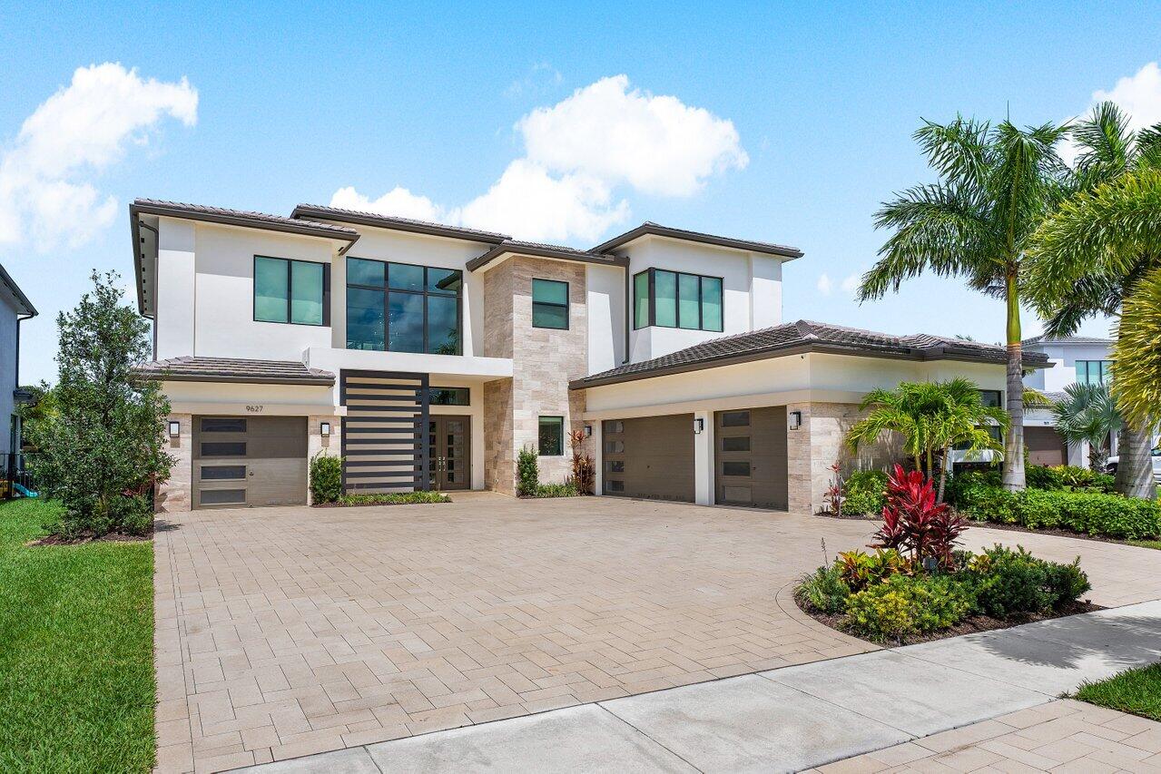 Introducing an exquisite modern estate nestled within the prestigious Boca Bridges, where luxury living meets chic elegance. As you approach, the exterior makes a grand statement with its oversized circular motor court, setting the stage for the luxury within. Stepping inside, you're greeted by a dramatic two-story foyer, hinting at the elegance that awaits throughout the home. The interior design exudes sophistication and grandeur, with designer finishes showcasing clean-lined warm color palettes that seamlessly unite to create a cohesive ambiance. This highly desirable Palermo floor plan is a perfect harmony between spaces, offering 6,200 sqft of living space with an elevator, 5 bedrooms, 6.5 bathrooms, media room, loft, and 2 laundry rooms. The expansive great room, designed with entertaining in mind, features a custom bar where guests can unwind and socialize in comfort and style. The heart of the home lies in the open-concept kitchen, where crisp white tones complement the stacked shaker cabinetry and double island, equipped with top-of-the-line SubZero, Bosch, and Wolf appliances, including a 48-inch gas cooktop, microwave drawer, and built-in double oven. The ample chef's kitchen flows seamlessly with the formal dining room and family room with retractable walls of windows blurring the boundary between indoor and outdoor living, allowing natural light to flood the interior and providing easy access to the outdoor space. A covered veranda invites alfresco dining and entertaining, conveniently offering retractable phantom screens and a custom outdoor kitchen. The expansive patio sets the tone for the custom heated saltwater pool with its inviting sun shelf and generously sized spa. Surrounded by lush palm trees and tranquil water vistas, the outdoor space offers a serene backdrop for relaxing and embracing the epitome of luxurious outdoor living. To experience the upper level of this magnificent residence you're presented with the option to ascend via the elevator or staircase with striking custom glass stair rail. As you arrive, the cinematic media room greets you, equipped with surround sound, top-of-the-line equipment, and amenities, including a 140-inch viewing screen, providing an immersive entertainment experience for residents and guests alike. A purposeful and sun-filled open loft, featuring a custom built-in workspace that doubles as a cozy den, provides a versatile space for work or relaxation. The primary suite offers an expansive retreat, complete with custom walk-in closets, a spa-like bathroom featuring double vanities, a luxurious jacuzzi soaking tub, and an oversized shower. The primary bedroom exudes serenity and comfort which opens to an oversized waterfront balcony, perfect for unwinding and soaking in the evening views. Three additional large ensuite bedrooms await on this level, each thoughtfully outfitted with custom closets and motorized window treatments. Additionally located on the upper level is 1 of 2 oversized laundry rooms, complete with a beverage cooler. 
Boca Bridges is the most prestigious of the GL Homes lifestyle communities. Offering a dramatic gated entrance with a manned gate and security patrol. The extensive amenities Boca Bridges offers include the state-of-the-art 27,000 SqFt clubhouse which boasts sophisticated resort-style amenities such as a full-service restaurant and lounge, poolside bistro, fitness center with studios offering a variety of classes, his & hers locker rooms with sauna and massage rooms, indoor sports court, card rooms, kids activity center, 7 tennis courts, 4 pickleball courts, multiple pools with kids splash park, outdoor sports court, kids playground and party pavilion.