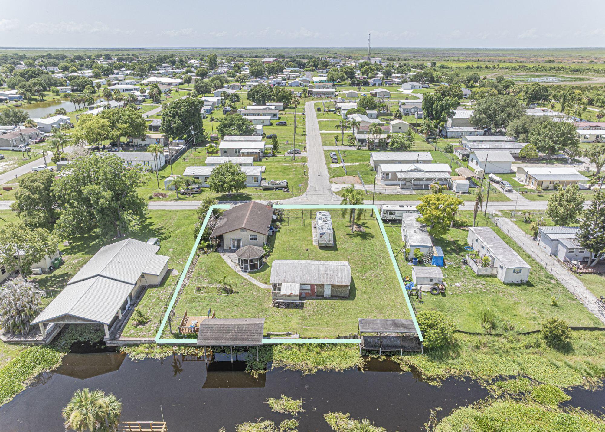 Future Fishing Campground! Waterfront property sits on 1/2 acre+/- fenced property in farm-friendly Okeechobee, FL! Manufactured 2/1 + carport comes w/ so many extras including RV pad, large shed/barn/garage, sundeck, octagon screened gazebo, 2 fishing/boat docks that lead to Lake Okeechobee. Rent in season as a quaint fishing camp retreat, weekend getaway, or investment opportunity. Seller had a 24 ft. boat (water depth approx 3-4 feet). Property comes as-is; buyer responsible for clean-out, verifying all rental/zoning restrictions + water depths. So much potential - a little TLC will go far!