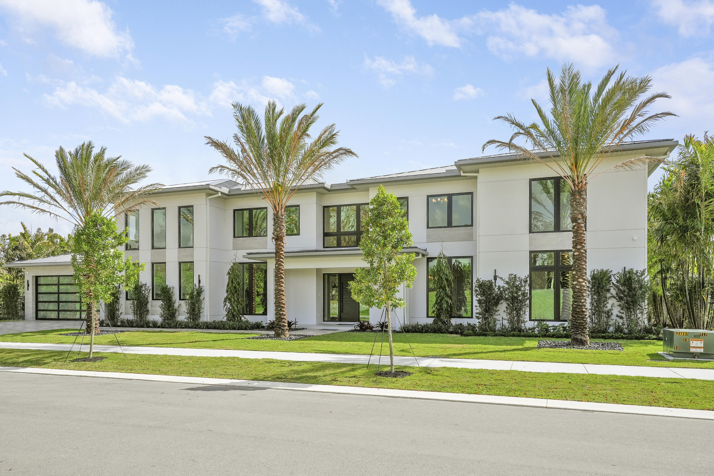 Farrell Estates at Palm Beach Polo presents an exclusive enclave of 27 bespoke residences. Lot 9 is a dramatic modern lakefront estate ideally located just 3 miles from the Winter Equestrian Festival and under 12 miles to Palm Beach International Airport. Spanning 7,492 SF, the home showcases soaring light-filled interiors, expansive porcelain floors, and walls of glass framing tranquil water views. The chef's kitchen and great room flow seamlessly to over 900 SF of covered outdoor living designed for sunset entertaining. The main level offers a private junior suite with sitting area plus a versatile flex space ideal for a gym or office. Upstairs, five ensuite bedrooms accompany a luxurious primary retreat with office or dressing room.  Double laundry rooms on both levels provide exceptional functionality. A rare opportunity for modern lakefront living within Palm Beach Polo.