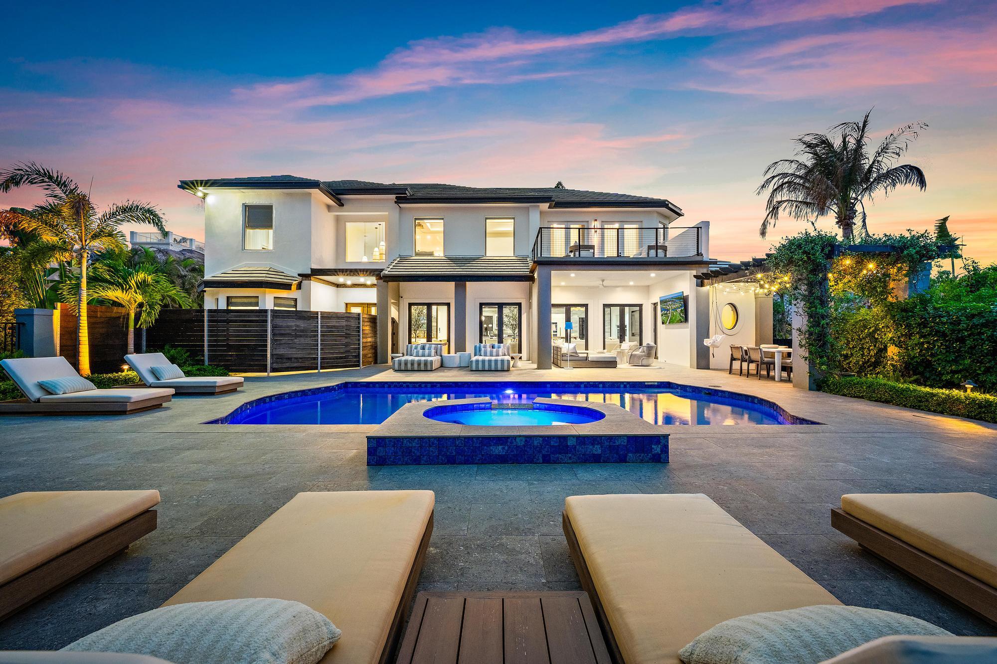 Welcome to an extraordinary private estate situated on nearly one acre with intracoastal views. This home is designed for luxury living and entertaining.  This exceptional 4-bedroom residence features a gourmet chef's kitchen, double islands, burled Brazilian walnut finishes and crystallo arabescato countertops.  Gorgeous marble countertops in the primary bath and powder room, and thoughtfully curated upgrades throughout.  A true golfer's paradise, the property boasts a 40 yard chipping and pitching green complete with 2 fully built out sand bunkers.  Enjoy evenings around the custom fire pit, stay active in the brand-new gym, and appreciate elevated finishes including Toto toilets and high-end details at every turn.  This one-of-a-kind estate is a MUST SEE!