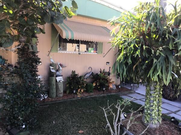 Affordable Florida Living for 55+ in the Heart of Stuart -Exceptional value in great area, conveniently located near restaurants, shopping, hospitals, churches, beaches. This spacious manufactured home features two spacious master bedroom suites, each with its own private bathroom. The bright, open floor plan makes excellent use of every square foot, with tasteful finishes and abundant natural light throughout. Enjoy the Florida lifestyle from two inviting patios: • The east patio overlooks lush tropical landscaping, making it the perfect spot for your morning coffee. • The covered west patio provides a comfortable place to relax and entertain year-round. The versatile Florida room is currently used as a large home office but can easily be converted into a third bedroom.  This home includes • Two side-by-side refrigerators • Full-size washer and dryer under air • Beautiful stained-glass entry doors • Multiple large storage rooms and a spacious backup pantry • Hurricane shutters and sunshades to help reduce air conditioning costs • Durable double-insulated metal roof • Two-car driveway with covered carport • Additional guest parking nearby The monthly rent of $828 includes: • Full access to community amenities • Lawn care • Trash removal One of the biggest advantages of this home is the cost savings: • No real estate taxes • No homeowner's insurance required