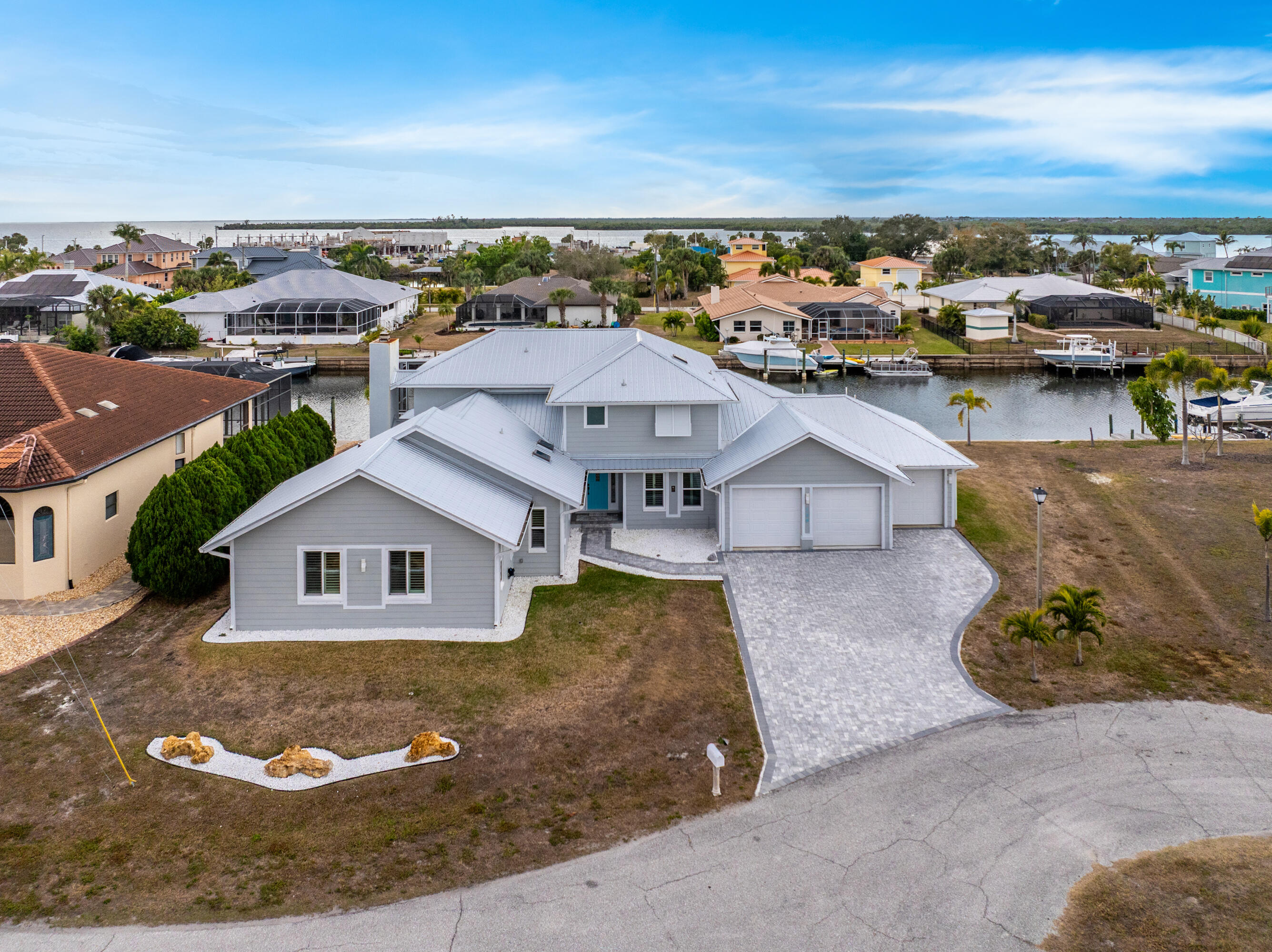 Experience refined waterfront living in this extensively renovated coastal estate offering 150 feet of waterfrontage with direct boat access to Charlotte Harbor and the Gulf beyond. Perfectly positioned to capture breathtaking sunset views, this exceptional residence blends upscale finishes, thoughtful design and the ultimate Southwest Florida lifestyle.  From the moment you arrive, the home makes a striking impression with its paver driveway, metal roof, impact-resistant windows and expansive three-car garage. Inside, the open-concept layout is filled with natural light and enhanced by designer touches throughout, including luxury vinyl plank flooring, custom millwork, plantation shutters and coastal-inspired accents that create a warm yet sophisticated atmosphere. A private flex space near the entry offers endless possibilities as a home office, media room or lounge. The main living area is designed for both entertaining and everyday comfort, highlighted by a fireplace, custom built-ins and seamless indoor-outdoor flow through elegant French doors. At the center of the home, the gourmet kitchen showcases quartzite surfaces, premium stainless steel appliances, open shelving and an oversized breakfast bar ideal for hosting guests. The adjoining dining space overlooks the resort-style outdoor setting, where the newly redesigned lanai and pool area create a true tropical retreat.  The upstairs primary suite offers a luxurious private escape complete with serene water views, a spa-inspired bathroom, soaking tub, oversized walk-in shower, dual vanities, steam room and an inviting private balcony perfect for morning coffee or evening sunsets. A custom wet bar and adjoining versatile retreat provide flexibility for a fitness room, nursery, sitting area or private workspace. Additional guest accommodations are generously sized and complemented by beautifully updated bathrooms throughout the residence.  Outdoors, enjoy a heated saltwater pool with tranquil water features, expansive paver decking and multiple seating areas designed for entertaining or quiet relaxation along the canal. Boating enthusiasts will appreciate the private dock and 16,000-pound lift, providing effortless access to open water with no bridges.  Ideally located near Punta Gorda, waterfront dining, shopping, parks, beaches and major travel routes, this one-of-a-kind property delivers luxury, comfort and premier waterfront living in one remarkable package.