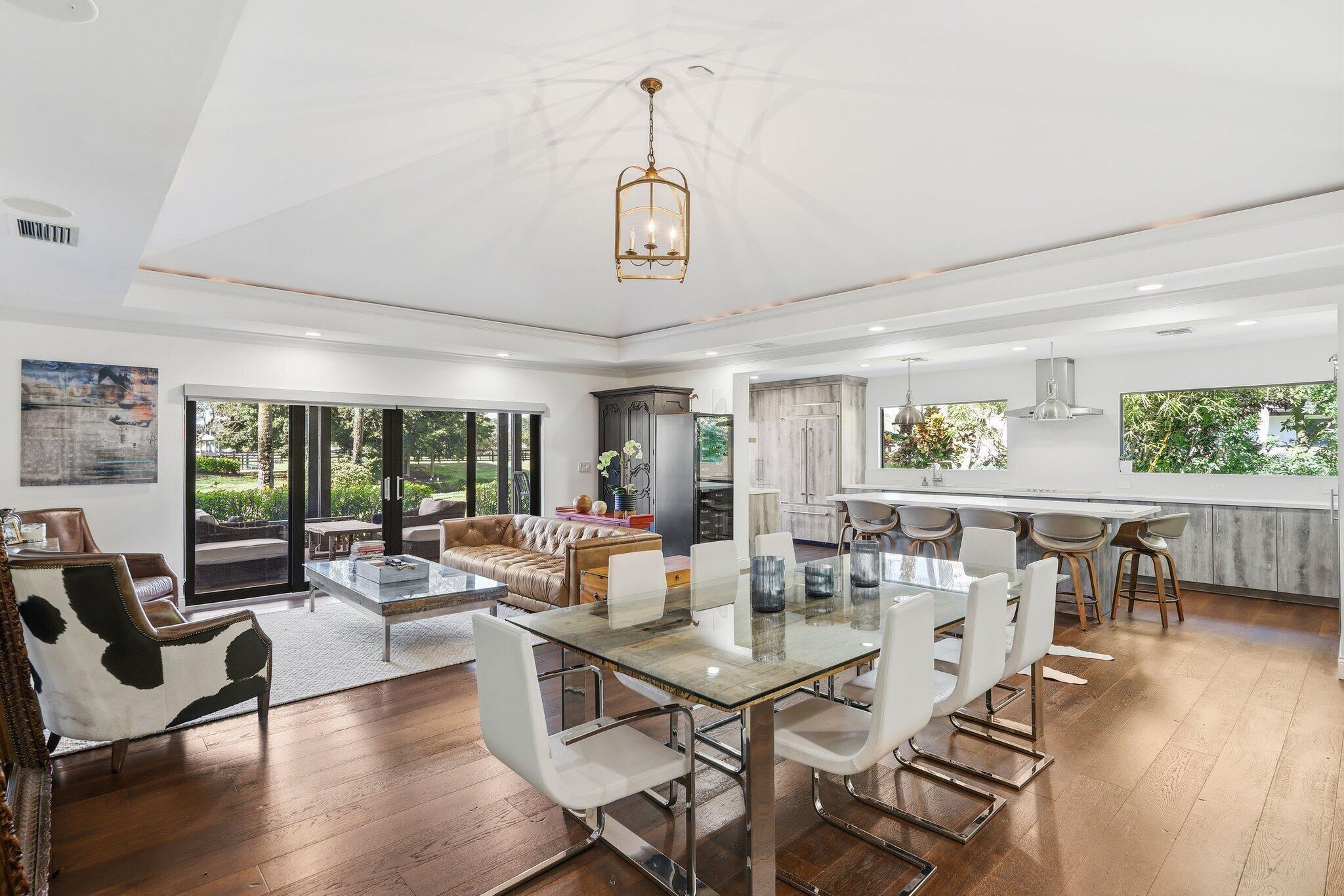 Remodeled 4BR, 4.5BA ground-floor end-unit incl. 1/1 guest suite w/ private entrance. Completely updated in 2020 with impact windows, modern kitchen/appliances, designer finishes. Split floor plan, elegant foyer, powder room. Open living/dining flows to private terrace w/ tranquil  views. Neutral palette, energy-efficient. Banyan-lined street, resort-style ambience. Move-in ready on Wellington's most prestigious street.