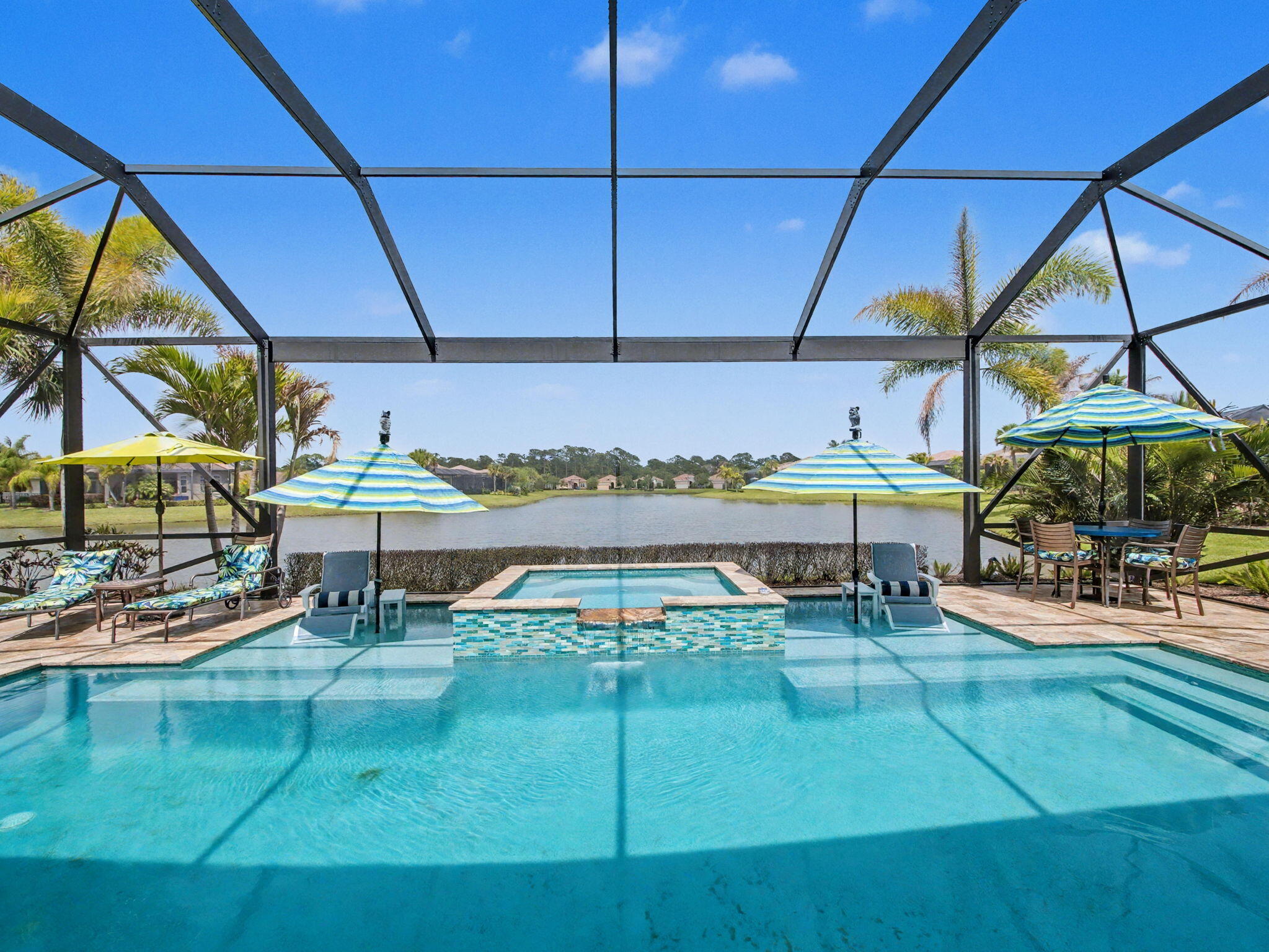 Experience elevated Florida living in this luxurious 3-bedroom, 3-bathroom lakefront pool home located in the highly sought-after PGA Verano community. At the heart of the home is a stunning $200,000 kitchen remodel featuring premium Wolf appliances, a Sub-Zero refrigerator, separate Sub-Zero beverage fridge and ice maker, a 145-bottle wine fridge, Bosch dishwasher, and a striking arched window addition that enhances both natural light and architectural appeal. The home continues to impress with a resort-style outdoor living space, including a designer tile swimming pool, expansive 15-person spa, and a custom travertine pool deck overlooking tranquil lake views.  Additional big-ticket upgrades include a new pool pump and special impact/safety windows surrounding the pool area, providing both peace of mind and luxury outdoor living.  Designed with both comfort and style in mind, this residence offers a seamless open-concept floor plan that effortlessly connects the living, dining, and kitchen areas—perfect for entertaining and everyday living.  Inside, the home is loaded with high-end finishes including custom plantation shutters, custom closet built-ins throughout, and a built-in office workspace. Upgraded lighting fixtures and fans add a modern touch, while upgraded wood flooring in the bedrooms enhances warmth and sophistication. The garage is equally impressive, featuring custom metal storage cabinetry for optimal organization.  Residents of PGA Verano enjoy access to world-class amenities, including a resort-style clubhouse, state-of-the-art fitness center, tennis courts, and scenic walking trails. Conveniently located near shopping, dining, and major highways, this home offers the perfect balance of luxury, convenience, and waterfront community living.