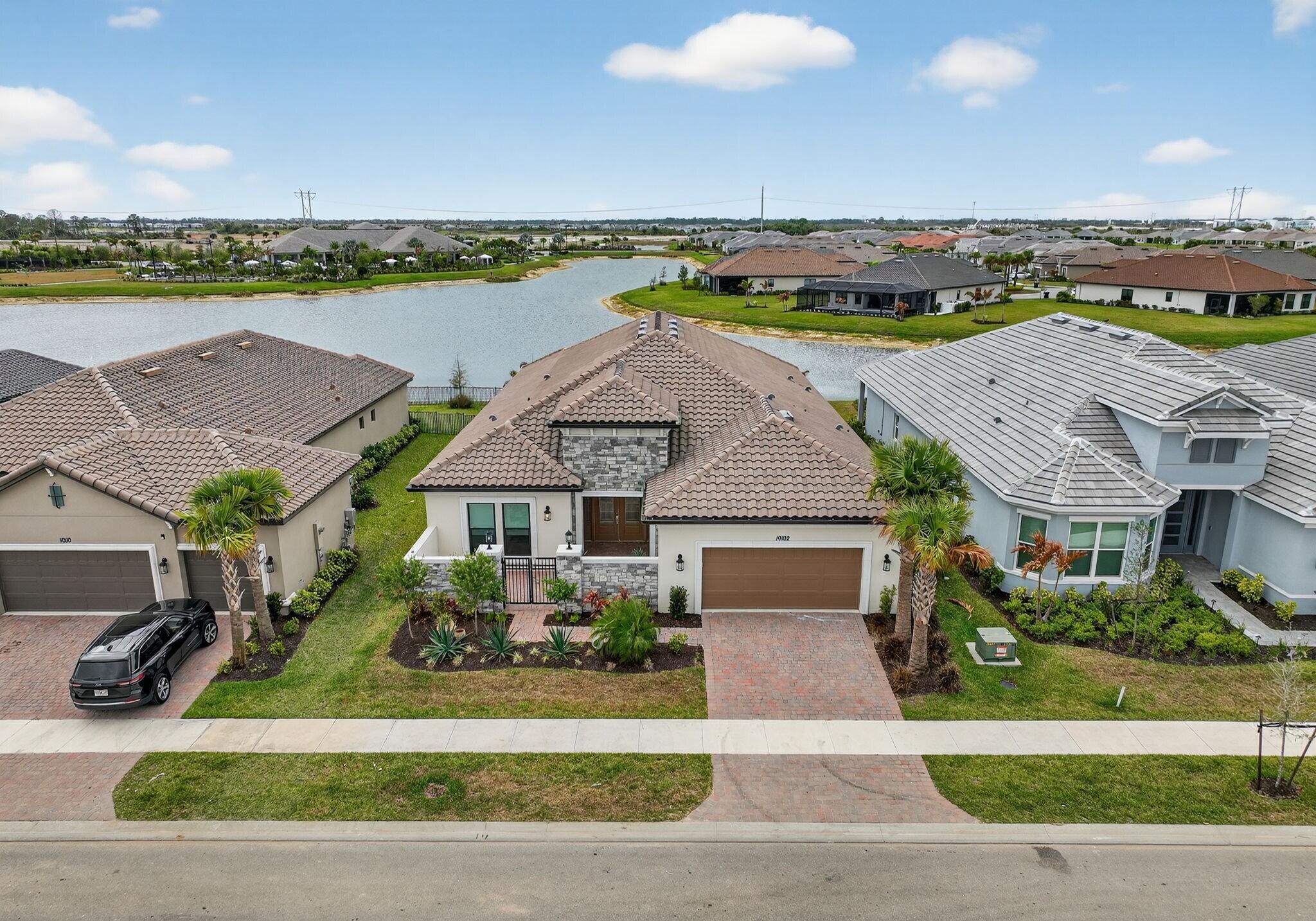 Meticulously curated from the ground up, this new construction lakefront estate in Esplanade at Tradition is in a class of its own. A private courtyard creates a grand arrival, while the backyard oasis stuns with a custom pool, expansive lanai, and designer summer kitchen featuring Dekton surfaces, built-in grill, sink, and motorized screens framing tranquil water views. Inside, zellige tile, two-tone cabinetry, an oversized island, and cypress beam and tongue-and-groove ceilings create an interior worthy of any design publication. Whole-house filtration, smart automation, and custom storage throughout. Enjoy a premier 55+ lifestyle with fabulous resort style amenities offering concierge services, resort pool, spa, café, pickleball, and more all in the heart of the Treasure Coast.