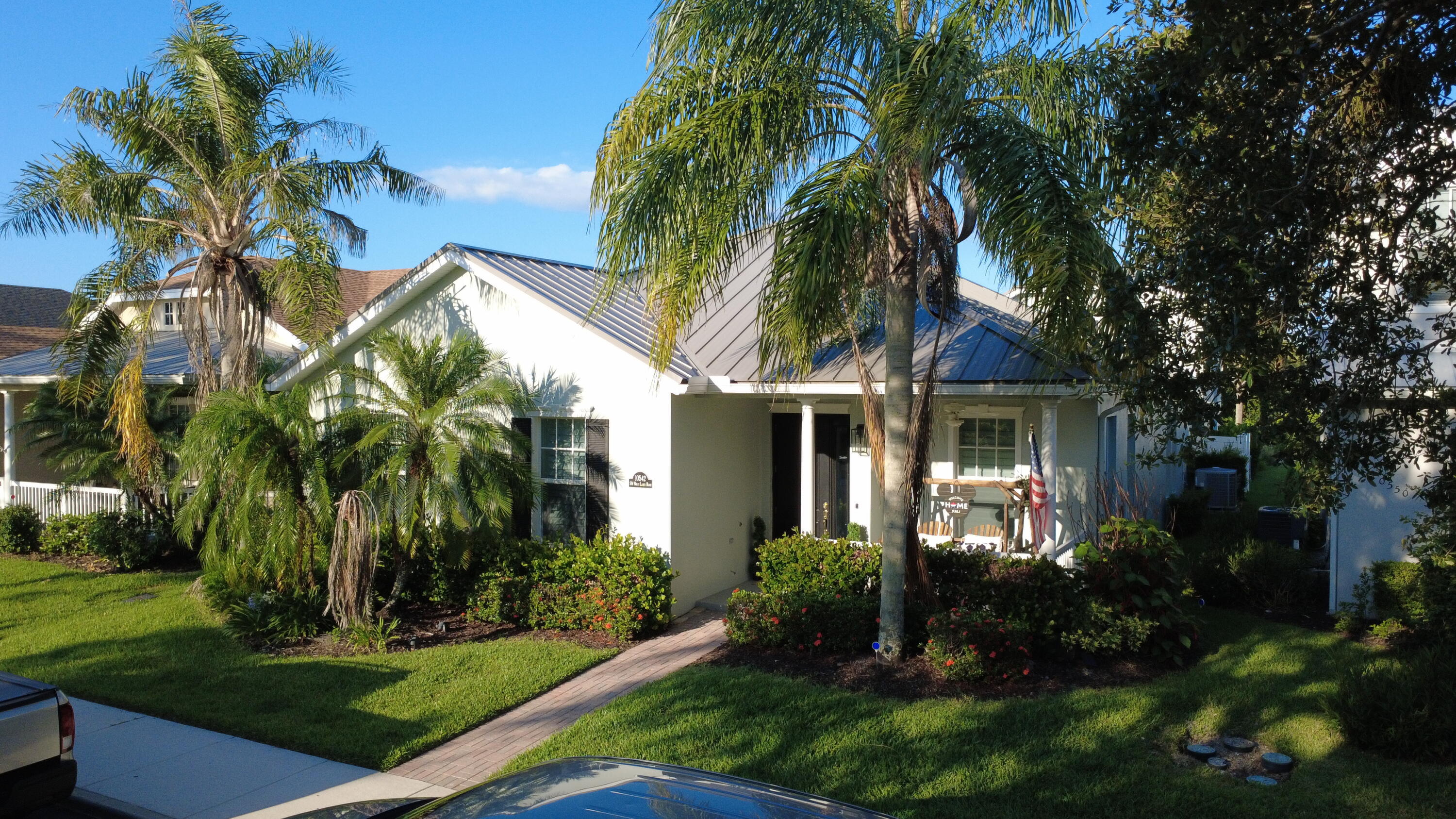 Bedford Park Gem! Rarely available upgraded 5-bed, 3-bath home with Separate private-entry apartment -2 Residences Connected by a covered lanai breezeway. The above garage apartment features 1 bed, 1 bath w/full kitchen, washer/dryer - perfect for guests, family, or extra living space. Main Residence is 4 bed, 2 bath. Kitchen boasts a quartzite island/countertops, gas range. Interior highlights of wood plantation shutters, crown molding, fresh paint. Primary suite features new flooring set in attractive herringbone pattern, dual sinks, soaking tub, separate shower, walk-in closets. fenced yard for entertaining. 2021 standing seam metal roof, 2025 exterior paint. Park views, this coveted intimate village of homes is within walking distance or golf cart ride to pool, park and dog park.  Minutes to Tradition Square and outdoor markets. This is a once in a lifetime opportunity to own essentially 2 homes in this quaint "front porch community".