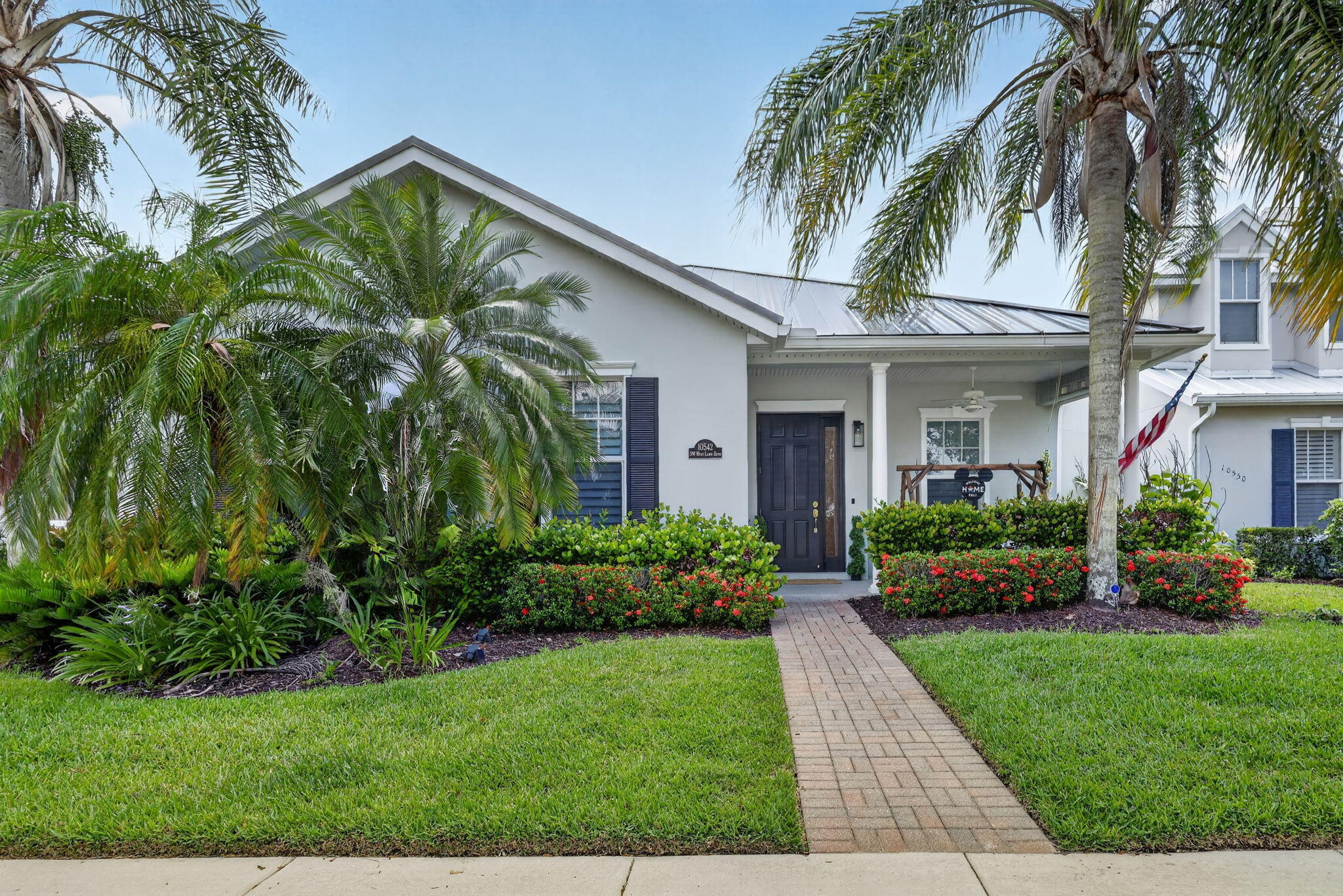 Bedford Park Gem! Rarely available upgraded 5-bed, 3-bath home with Separate private-entry apartment -2 Residences Connected by a covered lanai breezeway. The above garage apartment features 1 bed, 1 bath w/full kitchen, washer/dryer - perfect for guests, or extra living space. Main Residence is 4 bed, 2 bath. Kitchen boasts a quartzite island/countertops, gas range. Interior highlights of wood plantation shutters, crown molding, fresh paint. Bedrooms feature new flooring set in attractive herringbone pattern. Primary retreat invites w/walk-in closets, dual sinks, soaking tub, separate shower, and access to lanai. Private, fenced backyard, 2021 standing seam metal roof, 2025 exterior paint. Serene Park views from your front porch. This coveted intimate village of homes is within  walking distance/golf cart ride to pool, park and dog park. Minutes to Tradition Square and outdoor markets. This is a once in a lifetime opportunity to own essentially 2 homes in this quaint "front porch community".