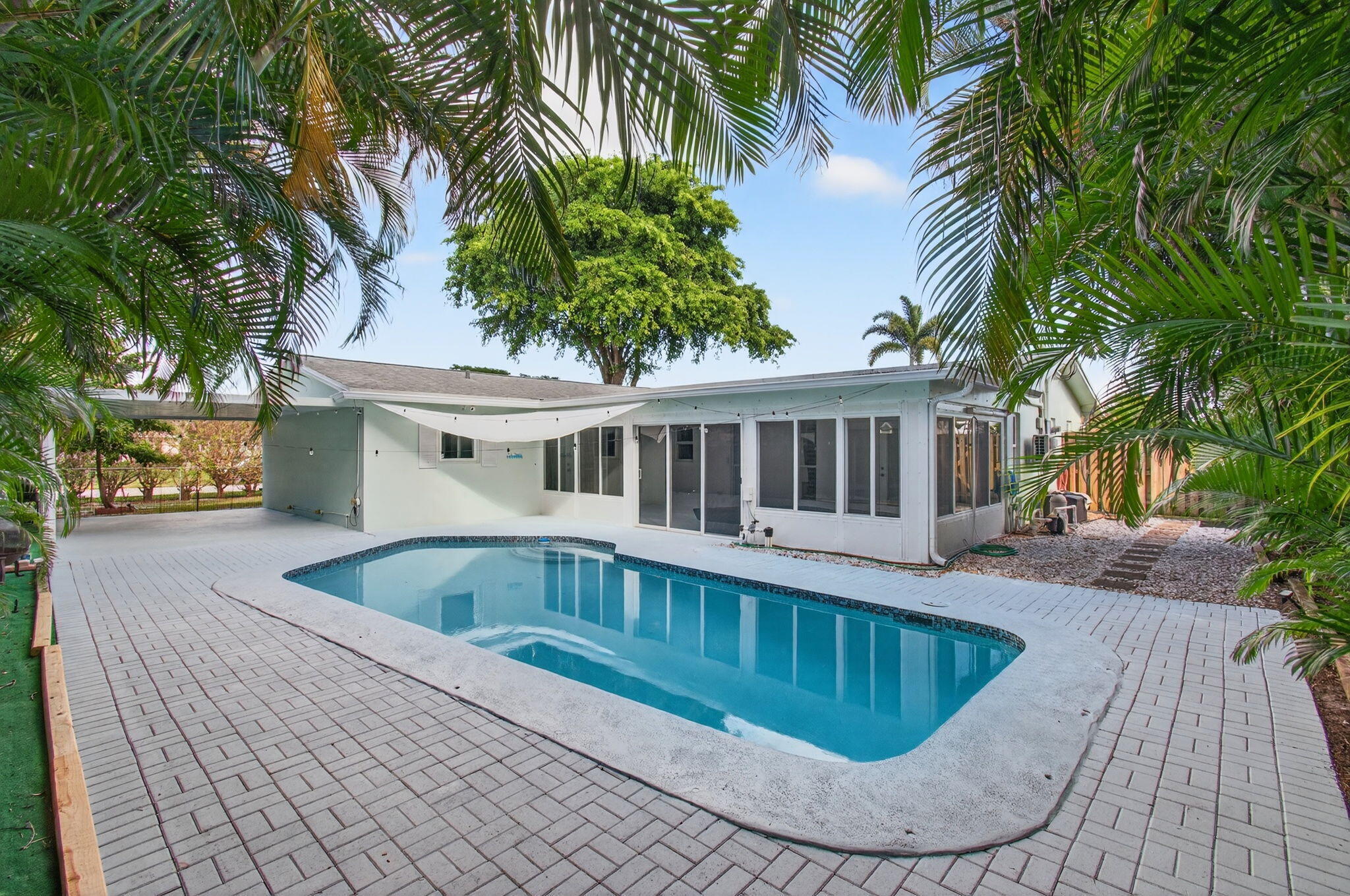 Beautiful 4BR/2BA POOL HOME in East Boca, available for annual rental in Country Club Village. Set on a corner lot with privacy hedges and a circular driveway with plenty of parking, this home offers comfortable indoor and outdoor living. Features include impact windows, Kevlar hurricane screens, plantation shutters, tile flooring throughout, a split-bedroom floor plan, and an inviting kitchen with stainless steel appliances, a new Whirlpool stove/cooktop, generous cabinet storage, and an indoor laundry/mudroom. The garage has been converted, with approximately 3/4 of the space used as a dedicated office/den and 1/4 used as a storage room, creating practical bonus space for work or hobbies. A bright, glass-enclosed Florida room with mini-split A/C offers additional living space overlooking the private pool, lush landscaping, and a covered patio for shaded outdoor living. Lawn and pool service are included. Pet-friendly with landlord approval. Meadows Park is adjacent to Country Club Village and offers a public pool, playground, tennis courts, picnic areas, and a nearby community garden. Conveniently located close to beaches, shopping, dining, I-95, Mizner Park, FAU, Boca Regional Hospital, and A-rated Boca schools.