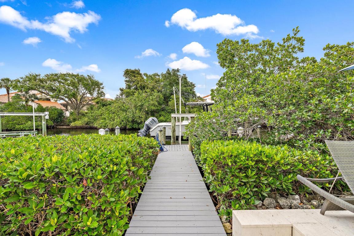 Discover the allure of waterfront living in Jonathan's Landing, where this exquisite custom home awaits, just minutes from the Inlet. The property boasts an impressive fifty feet of water frontage, enhanced by a robust 24,000-pound boat lift, an indulgent spa, an expansive pool, meticulously groomed landscapes, & a generously sized lanai, all oriented to capture the morning light from the east. The master suite is a realm of luxury unto itself, featuring high ceilings, wet bar, dual expansive walk-in closets, & an exclusive walk-in shoe sanctuary. Fine details are present throughout, such as chic diagonal marble flooring, custom crown molding, elegantly lit coffered ceilings, a convenient breakfast kitchen on the second floor with 3 bedrooms with en-suite baths. The home also features impact glass windows and doors and an instant hot water system, adding a touch of convenience to this luxurious setting. This residence strikes a perfect balance between grandeur and practicality, offering a refined lifestyle for those who appreciate attention to detail and a prime waterfront location. Baytowne has a community pool and a short golf cart ride away are the club amenities which  include: Bocce, Butterfly Island, dog park, fishing, kayaking, pavilions, playgrounds, recreational park, 257 dry stack slip marina, 3 Championship Golf Courses (JL Village, Medal & Match courses), 3 restaurants, 13,000 sq ft. wellness center, spa & salon, 10 Har-Tru tennis courts, 3 pickleball courts & the "JL Cares" organization.