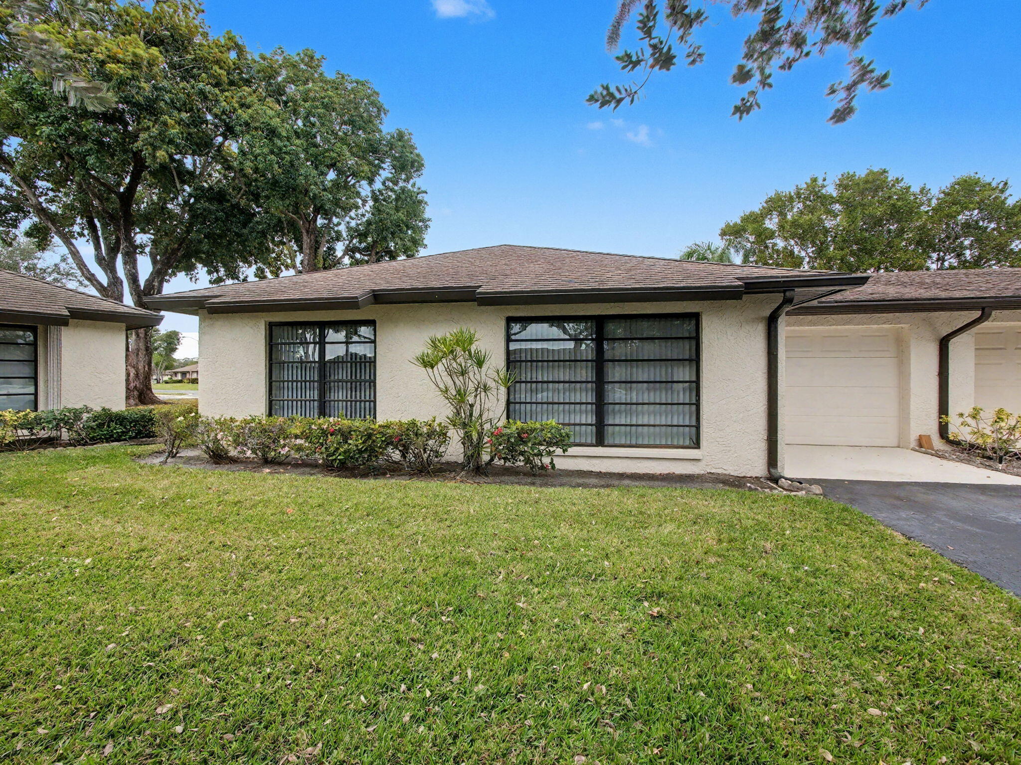 PRICED TO SELL! Don't miss this beautifully maintained 2-bedroom, 2-bath corner villa with a 1-car garage in the desirable 55+ community of Greentree Villas. Enjoy peaceful lake views from the enclosed patio, complete with storm shutters for added protection.  The updated kitchen features granite countertops, abundant cabinet space, and a conveniently located washer and dryer. Tile flooring flows throughout the living and dining areas, while both bedrooms offer comfortable carpeting. The spacious primary suite and updated bathrooms provide comfort and style.  Major updates include a new A/C installed in 2022. Greentree's low HOA fee covers roof maintenance, exterior insurance, water, cable, landscaping, trash removal, and maintenance of common areas. Residents enjoy access to six clubhouses and six swimming pools, creating an active and social lifestyle. Conveniently located near shopping, restaurants, entertainment, medical facilities, and major highways, including I-95. Exceptional value for a move-in-ready home with lake views and extensive community amenities!