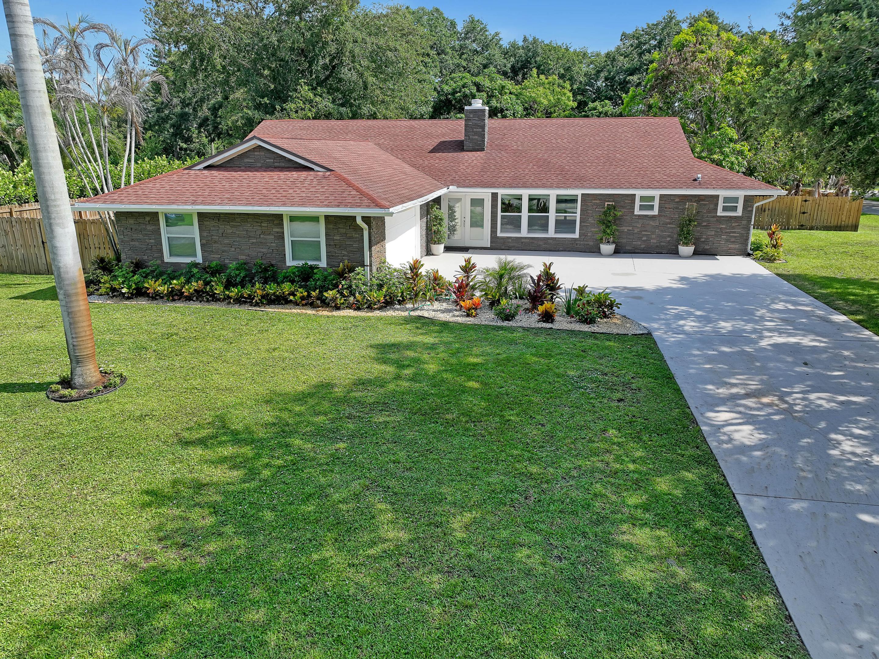 Welcome to 6185 White Oak Court in the heart of Jupiter, FL, situated on a half-acre lot. This beautifully transformed home has been completely renovated from the ground up and offers 5 bedrooms and 3 full bathrooms. Featuring porcelain tile floors throughout, brand-new hurricane-impact windows and doors, a stunning kitchen with brand-new stainless steel appliances, quartz countertops, and a large island overlooking the great room, this home is designed for both everyday living and entertaining. The great room also features a real wood-burning fireplace. Additional features include a dedicated dining room, wet bar, and cocktail lounge area. The oversized primary suite offers a spa-like bathroom with a large glass-enclosed shower and separate soaking tub. Step outside to your  oversized, fully fenced backyard a blank canvas ready to create your own private oasis, complete with two mature mango trees. Little Oaks residents enjoy access to a community boat ramp, making it perfect for boaters. Conveniently located just minutes from the beach, shopping, grocery stores, I-95, and the Florida Turnpike. Don't miss this incredible opportunity to own a fully renovated home in one of Jupiter's most desirable locations.