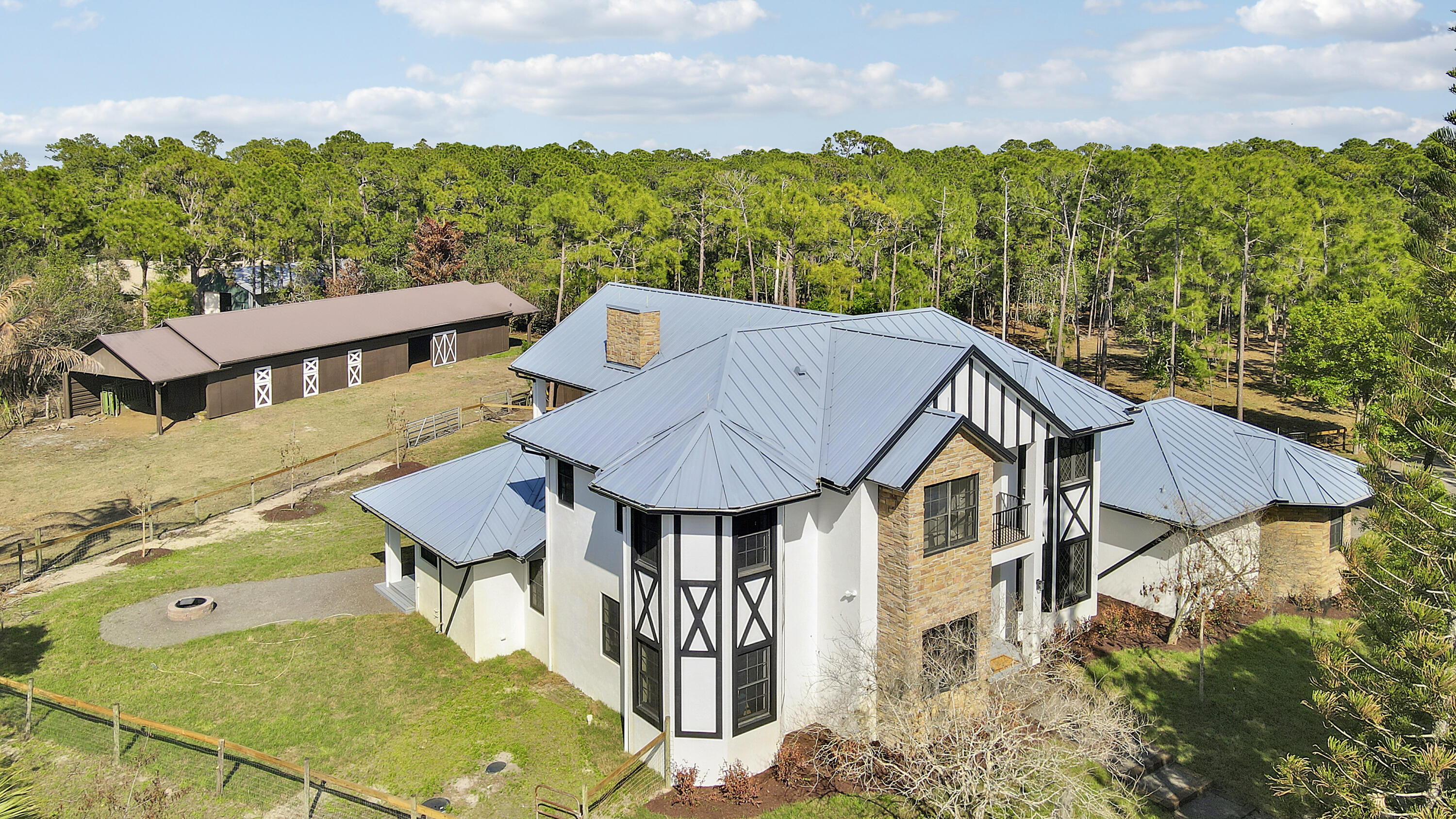 Welcome to this exquisitely renovated modern farmhouse estate, where refined luxury meets peaceful country living. Ideally located on a quiet, private street just minutes from I-95, fine dining, shopping, and everyday conveniences, this exceptional property offers the perfect balance of privacy and accessibility.  Set on 5 fully fenced private acres, this stunning residence features 5 oversized bedrooms, 4.5 bathrooms, and 4,169 square feet of thoughtfully designed living space, all completely renovated with impeccable attention to detail.   Every room and bathroom throughout the home has been beautifully updated, creating a seamless blend of modern sophistication and timeless farmhouse elegance. The home is filled with natural light thanks to all-new impact windows and sliding glass doors, offering both energy efficiency and peace of mind. Enhancing the home's fresh and refined aesthetic are all new lighting fixtures and ceiling fans throughout, along with brand-new flooring and carpet. The entire interior and exterior of the home have been freshly painted, providing a crisp, move-in-ready finish.  At the heart of the home, the beautifully redesigned kitchen features a stunning island, a spacious custom pantry, and a separate wet bar, making it perfectly suited for both everyday living and entertaining. The living room is anchored by a new gas fireplace, creating a warm and inviting focal point ideal for gatherings and relaxing evenings.  Designed with flexibility in mind, the home also features a newly added upstairs bonus room, offering additional living space that can easily serve as a media room, home office, playroom, or guest retreat.  Outdoor living is just as impressive. Enjoy the newly completed front patio and expansive back deck, ideal for entertaining or relaxing while overlooking the peaceful acreage. The property has been enhanced with brand-new landscaping and a custom fire pit, creating a welcoming outdoor gathering space. The metal roof has also been recently repainted, adding to the home's well-maintained and updated appeal.  Privately positioned off the road with its own private driveway, this exceptional estate offers both tranquility and convenience. The five fully fenced acres include a separate barn and paddocks, providing ample space for horses, farm animals, or simply enjoying the beauty and privacy of your own countryside retreat.  This is a rare opportunity to own a fully renovated luxury farmhouse estate that seamlessly combines modern upgrades, expansive living spaces, and the serenity of country living — all in an exceptional and convenient location.