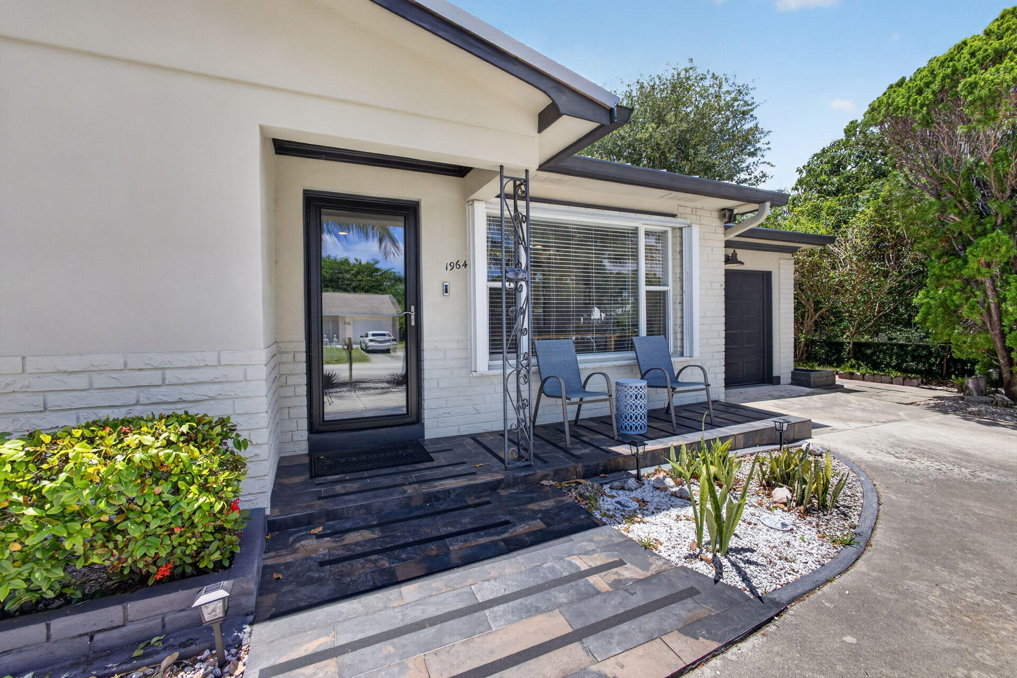 Beautifully maintained three bedroom, two bath home with a 1-car garage and desirable split-bedroom floor plan located in sought-after Unincorporated North Palm Beach with no HOA restrictions. Attractive curb appeal welcomes you with a circular driveway, lush tropical landscaping, and ideal northern exposure. This move-in ready home features updated cabinetry, granite countertops, subway tile backsplash, stainless steel appliances,  custom wood walls in dining / living rooms, custom crown moulding throughout and hurricane shutters. Recent improvements include a new A/C system (2025), flat roof (2024), and durable metal roof (2018). The primary bath offers contemporary finishes, a sliding barn door, and an updated walk-in shower.  Step outside into your own private retreat where the backyard has been thoughtfully designed for relaxing and entertaining. Enjoy the custom Tiki Hut (2019) and spacious wood decking that extends to the primary suite, creating a peaceful lounge area with private access. Conveniently situated just moments from Juno Park, the Intracoastal Waterway, and a mile from the beach, this home combines comfort, charm, and an unbeatable coastal location.