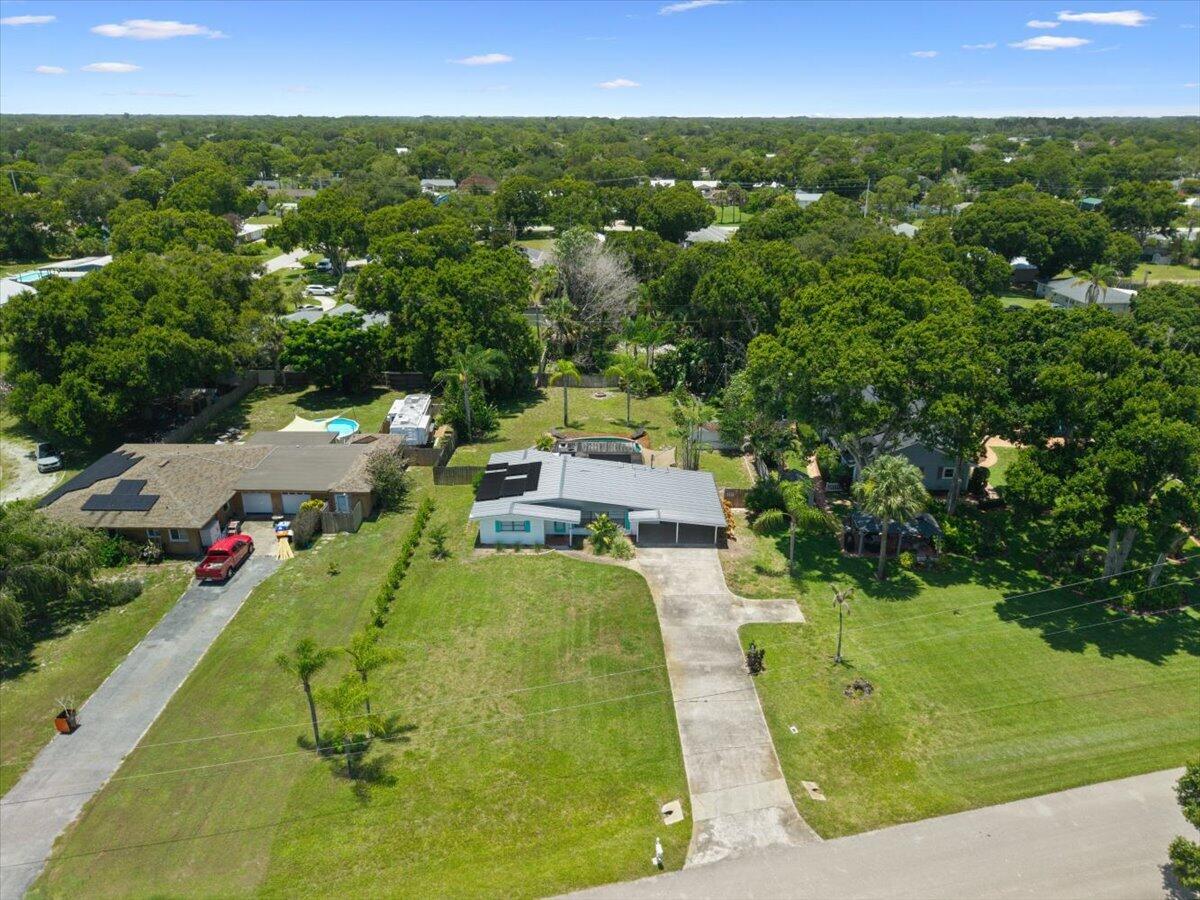 For those seeking the classic Florida lifestyle with room to breathe, room for the toys, and none of the restrictions of an HOA, this beautifully updated mid-century ranch checks every box. Situated on a spacious half-acre lot, this solid CBS pool home blends timeless character with today's most sought-after upgrades, making it the perfect fit for boaters, outdoor enthusiasts, and anyone looking for move-in-ready peace of mind. Recent improvements include a 2023 metal roof, brand-new HVAC system, electrical panel, irrigation pump, pool pump, whole-home water filtration system, and solar panels, along with a less-than-one-year-old water heater. Decorative Hardie Plank siding adds fresh curb appeal, while new luxury vinyl plank flooring in the bedrooms completes the interior with durability and style.  Outside, your private backyard retreat features a sparkling pool, a generous 25' x 13' covered patio ideal for year-round entertaining, and a wood privacy fence that creates a secluded setting to relax and unwind. The extra-long driveway offers abundant parking for boats, RVs, trailers, and guests—an increasingly rare feature this close to the water.  Location is where this property truly shines. McKee Botanical Garden is scenic 2 mile bike ride away, while the Intracoastal Waterway is close enough for paddleboard adventures. Spend your mornings at South Beach Park just 3.5 miles away, launch your boat from nearby public ramps or the Vero Beach City Marina within minutes, and enjoy an afternoon exploring local restaurants, shopping, and everything that makes Vero Beach one of Florida's most desirable coastal communities.  Offering the freedom of no HOA, extensive recent upgrades, and an unbeatable blend of space, convenience, and coastal lifestyle, this is the kind of Florida home buyers wait for.