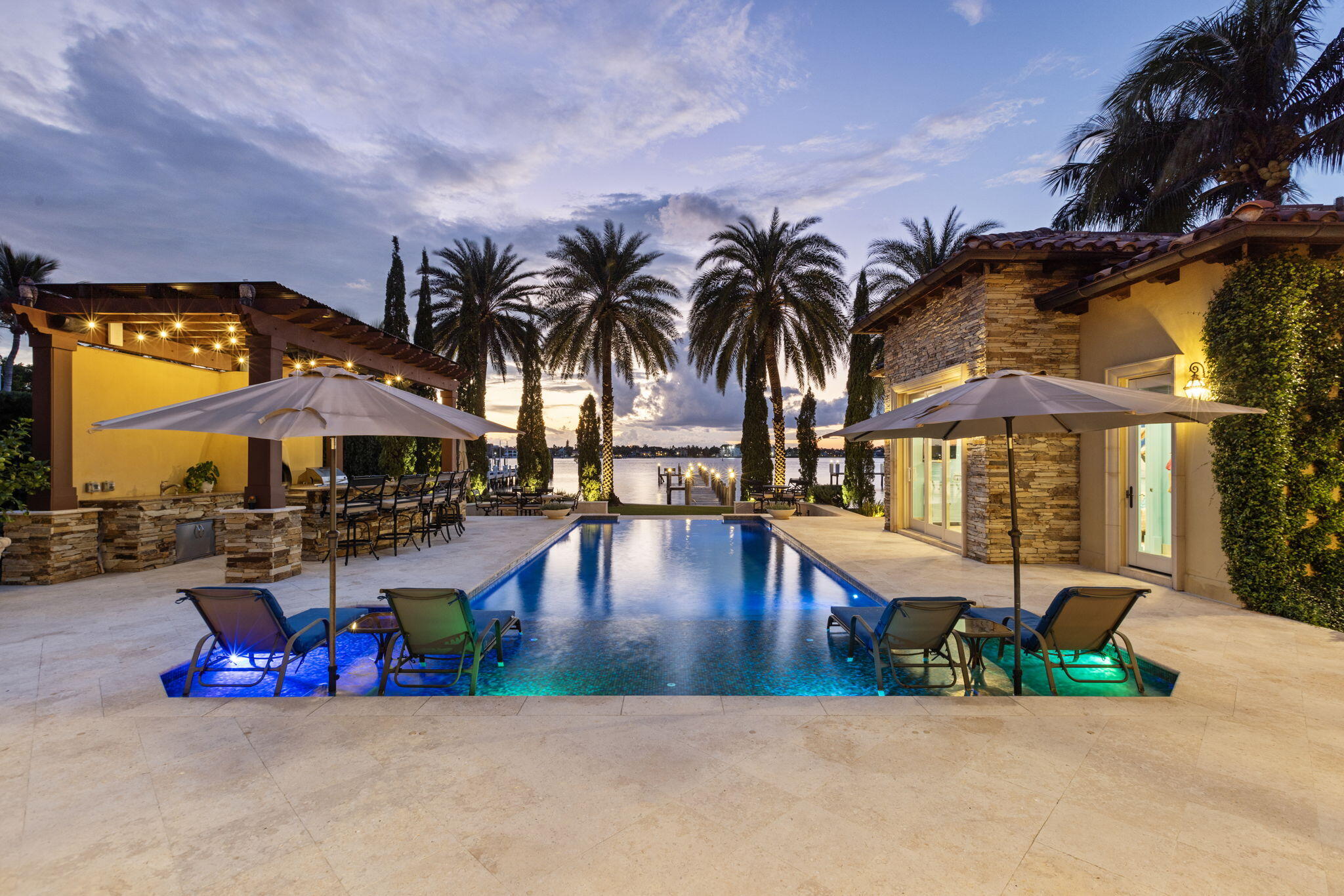 Presenting one of the finest properties on the entire island. We are now offering a truly unique opportunity to own a stunning waterfront Tuscan inspired estate on the wide water intracoastal. Expertly designed by award-winning architect Randall Stofft and crafted by renowned builder Rodney Sarkela, this custom-built masterpiece has never been on the market before and spans over 7,300 total square feet with a resort-like backyard. Spectacularly located just a few properties off the point of North Atlantic Drive in a no-wake zone setting on Hypoluxo Island. Perched with exceptional elevation, this residence commands direct west-facing intracoastal views offering sensational sunsets and an expansive backyard paradise with deepwater dockage to accommodate multiple water toys. Enjoy a heated saltwater pool & spa, an air-conditioned covered loggia with privacy screen, full summer kitchen with a wood-fired pizza oven and a full bar. The property also includes a separate air-conditioned pool house with a full bath, kitchenette and TV lounge area. 

Be wowed by immediate water views and a soaring 30-foot foyer leading to a formal living space with a natural gas fireplace, hidden temperature-controlled back-lit wine cellar and plenty of room for entertaining. The living room pairs flawlessly with an elegant cocktail lounge complete with a full bar, all while facing the water. The formal dining room is walled with beautiful Venetian-plaster and features a dazzling crystal chandelier set with 24-karat gold infused coffered ceilings. The chef's kitchen includes a full butler's pantry with tons of storage, all upscale appliances, a massive granite island with plenty of seating, Swarovski crystal knobs and  an elegant breakfast nook with breathtaking views of the pool and intracoastal. Additional first floor highlights include fully retractable 10-foot impact-glass sliders for seamless indoor & outdoor living, imported marble flooring, a VIP guest suite, two separate offices that could convert to additional bedroom, powder room, oversized laundry room with laundry chute, refrigerator and an air-conditioned two-car garage.

Upstairs you are greeted with three additional spacious ensuite bedrooms and an additional den with beautiful natural hardwood floors. The upstairs primary suite is complete with his and her full separate baths, custom finished closets, high vaulted ceilings and a large balcony with unobstructed intracoastal views.

With 12+ foot vaulted ceilings throughout, 2nd floor fully concrete, elevator, automatic window/shade treatments, whole house Culligan water filtration system, Control4 and Crestron automation with built in Sono's speakers inside and out, this home blends sophisticated grandeur with modern coastal living. Just minutes to Palm Beach and to Delray Beach,  the 5-star Eau Hotel and Spa, high-end shopping and dining alike, major airports and I-95, Hypoluxo Island is a haven unlike any other. Enjoy "turnkey" living in this timeless waterfront dream.