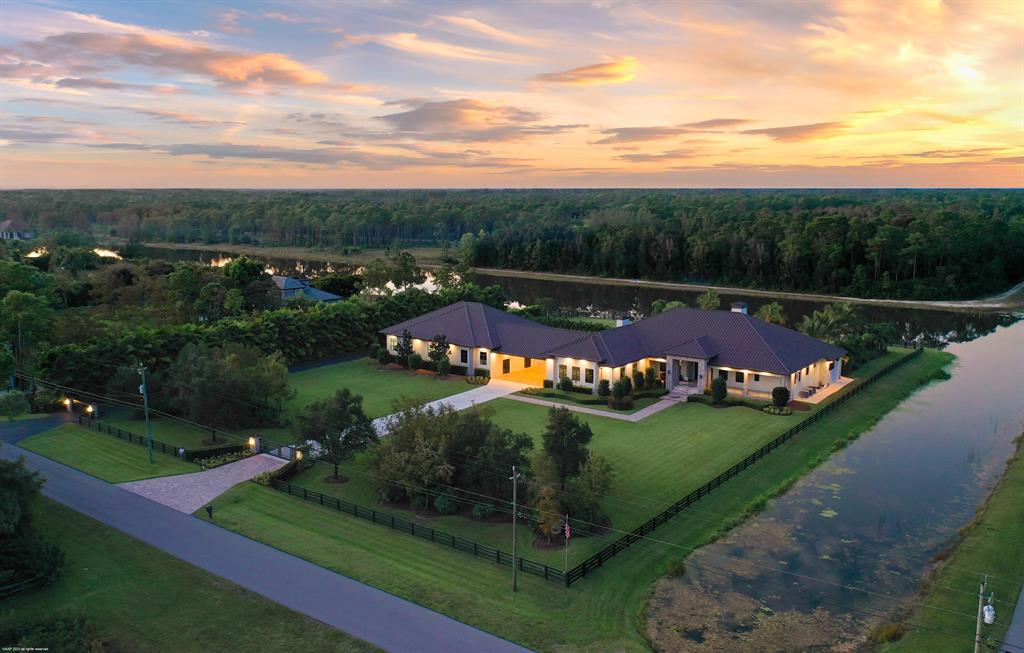 Beautiful lakefront home in the gated equestrian community of Homeland! 4 years new the home offers an open concept floorplan for ease of living with resort-like outdoor areas with stunning sunset views over the lake. The home boasts tile floors throughout, ctr-island kitchen w/ quartzite counters, gas cooking, double refrigerators, 2 fireplaces, impact windows & doors, 14' ceilings & a luxurious master-suite.  You'll love entertaining poolside with the water & fire features, summer kitchen, firepit, tiki bar & dock. The main house  is 4,845sqft/ac & mancave is 1,220sqft/ac. Also under air are the firing range & dog kennels. The RV/hangar garage & workshop with 14'x24' hangar door offer the ability to house up to 17 cars on property. A must see for the active family w/ all the toys! Summary of Additional Home Features:

An additional 2,735 sq.ft. of possible living space left unfinished for your custom buildout in the secondary building - perfect for guest house, in-law quarters or home business - endless possibilities.

Central vacuum
Sonos Sound throughout 
26 security camera system
16' entry ceiling, 14' in living areas
2 Wood & Gas fireplaces
Staking sliding doors opening to 16'
Office with custom built-ins

6 burner Thermador cooktop with griddle
Pot filler, double ovens & refrigerators
2 Kitchen sinks, wet bar with wine cooler
Summer kitchen with bbq with gas line, 2 burner, refrigerator & sink.

Laundry room: LG washer & Dryer, refrigerator & sink

Master Suite: electric blinds, wet bar with sink & refrigerator, dual vanities, dual shower heads, 2 large walk-in closets one with built-in Liberty safe.
 
 House garages have 16' x 12' doors - 8 car capacity.

The Pool:
50' x 25' saltwater party pool - slopes to 4'.5"
Pebble tec surface with glass tile. Gasline for pool heater installation, 4 firepits, 8 illuminated water spouts, 6 LED lights - all automated by cell phone.
Hot tub on master side of screen patio along with cabana 1/2 bath & outdoor shower.
Patio & pool deck with sound system.  
12'x24' sun deck.
Tiki bar with sink & refrigerator. Both the Tiki hut & dock have running water & electric, speakers and ceiling fans.  20' x20' Tiki dock extends 40' into the water.
Firepit with gas line.  Multiple Tiki torches.


Secondary Building:
1,220 Sq. Ft. Mancave/club room with 1/2 bath & kitchenette area with sink & refrigerator. 
Air-conditioned 6' Single lane firing range with ballistic sound buffering mats & automated target retriever & exhaust system.
Mancave & firing range act as hurricane safe rooms with poured concrete walls & 10" concrete ceiling.

Workshop / Garage: 9 car capacity, 50 Amp Motor home hookup. Room for 9 cars, or a helicopter with 14' x 24' hangar door on remote & 18' ceilings.
Air-conditioned Dog kennel wing with 4 kennels and room to add more, plus vet room & isolation rooms with stucco walls. (The Dog kennels are not for commercial use). 1 camera in isolation room and 2 in kennel area. 95' x 25' grass dog paddock with hose bib. Kennel has a drainage system to dual 500 gal tanks with a lift to the main drain field.

11 televisions with DirectTV
3 Zones AC in the house.
3 Mini splits in dog kennels - Dykin
1 Mini split in gun range - Mitsubishi 
Mancave has own AC Compressor - Courrier

Electrical:
Exterior Lighting Package - all on timers.
Landscape up-lighting, front & rear columns of house, front entry, front steps, gate columns, soffit downlights & soffit outlets for holiday lights.
600 Amps to main house
No exposed electrical conduit in hangar garage - run inside the block.

Generac 100KW whole house generator - 1000 gallon tank.  System is linked to cell phone.

The house is stem-wall construction & 4' above street elevation. 2' pitch to the road. All down spouts drain to the canal or lake.
Front exposure is south & the rear is north. 

Circular driveway with two electric gated entries. 

2,735 sq.ft. of unfinished area ready for buildout:
Loft area hangar garage (1,534sq.ft.) and adjacent 40' x 30' bonus room above the portico breezeway (1,200sq.ft.). Water & sewer is stubbed. 

A detailed list to be provided at showings. 

All sizes & numbers are estimated and the responsibility of the buyer to confirm in the due diligence period.