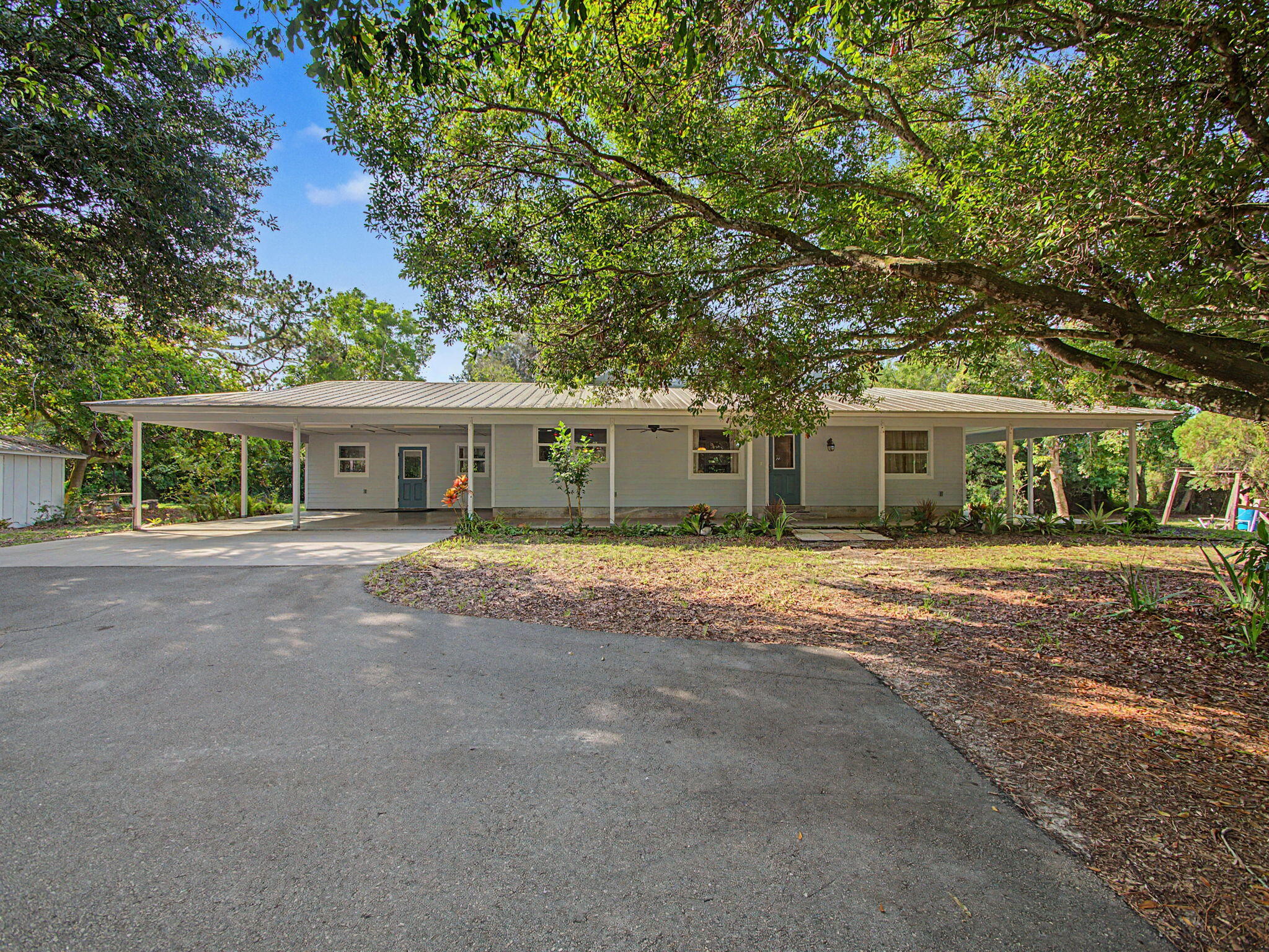 Rare 2.25-acre estate in the heart of Stuart offering endless possibilities! Zoned A-1A (Agricultural District) with NO HOA, this exceptional property features a beautifully updated 4BR/2BA home, 1987sqft, & two detached air-conditioned garages/workshops totaling approximately 2,800 sq. ft. with five bays & 3-phase electric. This meticulously crafted home showcases a gourmet kitchen with quartz countertops, center island cooktop, double ovens, custom cabinetry, Mirage wood flooring throughout, vaulted ceilings, impact windows & doors, & a luxurious owner's suite. 3 additional carports, asphalt driveway, city water, well, septic, storage shed, & room for a pool! Ideal for car collectors, boats, RVs, equipment, horses, horticulture, home-based businesses, & other permitted A-1A uses. The chef's kitchen is beautifully appointed with stainless steel appliances, a center island cooktop, double ovens, quartz countertops, custom wood cabinetry with elegant glass display doors, soft-close drawers, pull-out spice racks, and abundant pantry storage. Throughout the home you'll find Mirage wood flooring, solid oak interior doors with crystal knobs, designer lighting, ceiling fans, vaulted ceilings, and impact windows and doors, & level 5 drywall. Attention to detail at every corner of this home! The spacious owner's suite features dual walk-in closets, dual vanities, an oversized walk-in shower, and a luxurious garden soaking tub surrounded by beautiful sky blue Corian with a picturesque window overlooking the property. Three additional bedrooms provide flexibility for family, guests, or a home office, with one currently configured as a private office with glass French doors. The oversized laundry room includes a utility sink, storage closet, and a stainless-steel refrigerator with ice maker. The detached air-conditioned garages/workshops measure approximately 1,500 and 1,349 square feet and feature five oversized garage bays with 10- and 11-foot ceilings, 3-phase electric, attic storage, and exceptional space for collector cars, boats, RVs, trailers, equipment, hobbies, horticulturists, or a home-based business where permitted. Outside, enjoy the expansive wraparound porch overlooking 2.25 private acres with mature shade trees, no wetlands, asphalt driveway with culvert, three carports, numerous hose bibs, & a separate storage shed! Plenty of room to add a pool. A private residential compound where you can keep horses or livestock while securing Greenbelt tax relief, this property offers outstanding flexibility. Bring your pets, horses, numerous cars, boats, RVs, toys, and imagination! You will be impressed by this amazing property and rare opportunity on the Treasure Coast! Buyers should verify all intended uses with Martin County. Book your private tour today!