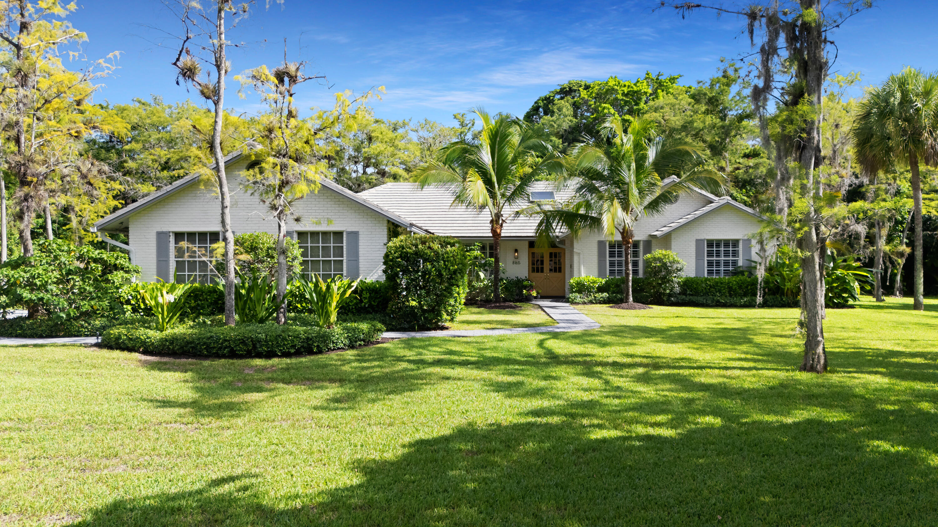 Located in the exclusive gated community of Whispering Woods, this beautifully updated 4-bedroom, 2.5-bathroom pool home sits on over an acre of private, lushly landscaped grounds. The modern kitchen features an expansive center island and top-of-the-line stainless steel appliances, making it ideal for both everyday living and entertaining. The spacious primary suite offers his-and-hers separate vanities with walk in closets, and a shared walk-in shower. Additional highlights include vaulted ceilings, a working fireplace, and beautifully renovated bathrooms with new tile, vanities, and fixtures. The guest bathroom also serves as a convenient cabana bath. Step outside to your fenced pool, complete with a summer kitchen and expansive backyard, creating the perfect setting for entertaining.