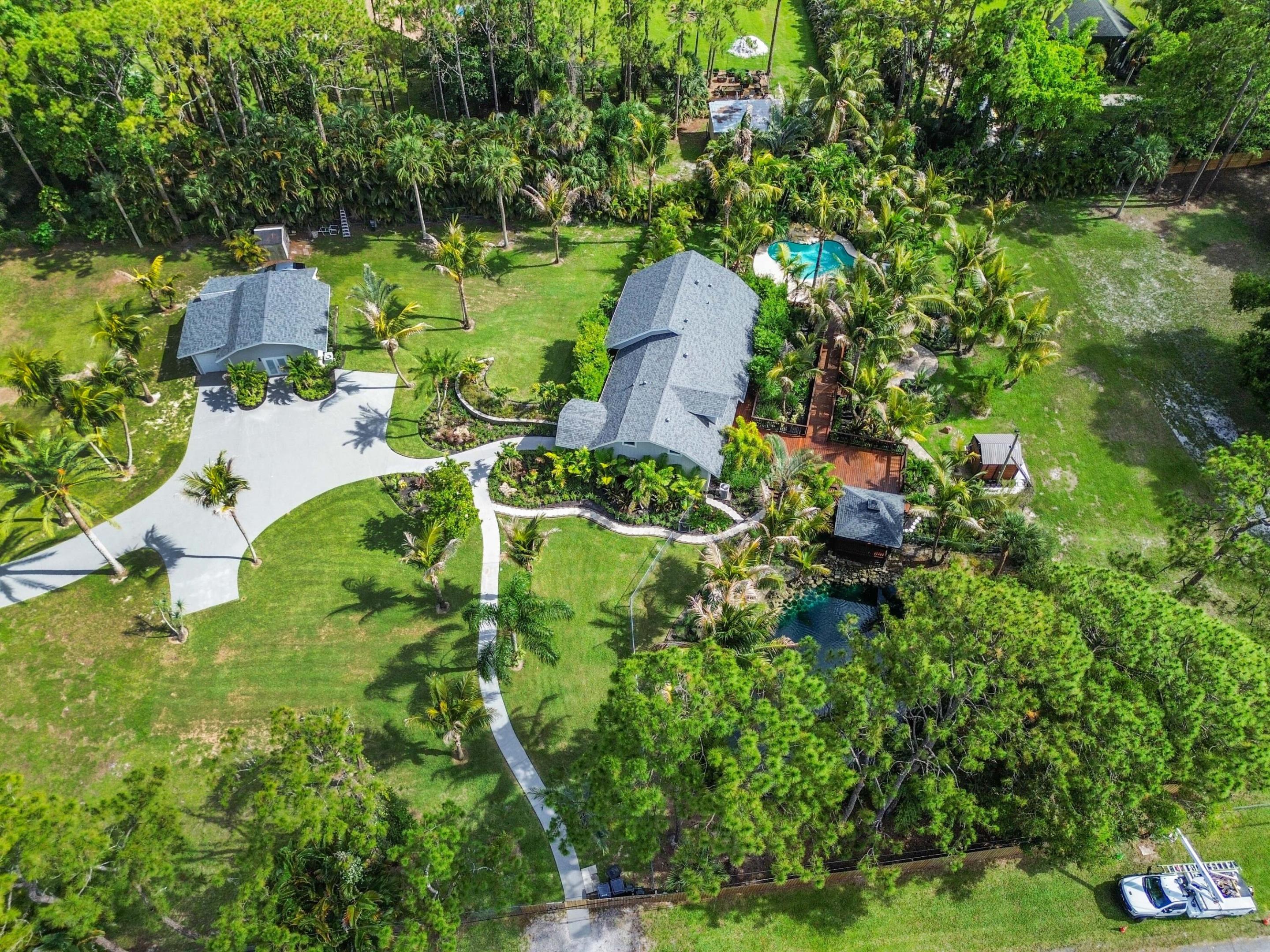 Experience resort-style living on this stunning private estate situated on 1.94 acres with no HOA and breathtaking waterfront pond views. NEW ROOF & AC UNITS!!! Behind a private gate, this beautifully redesigned estate, offers over 3000 sq ft of living space with 4 bedrooms and 3 bathrooms, surrounded by lush tropical landscaping and incredible outdoor spaces that create your own private oasis.  From the moment you enter through the foyer, you'll appreciate the extensive upgrades throughout the home. The custom kitchen is designed for both everyday living & entertaining, featuring a granite island, built-in oven, range with chimney hood, 2-door refrigerator/freezer, wine refrigerator, real wood cabinetry for storage, & a washer and dryer conveniently located in the kitchen area.  The private master suite is on the first floor with a stunning ensuite bath. Also on the first floor is a bonus room that can be used as a 4th bedroom, game room or media room.   French doors and complete hurricane impact windows and doors fill the home with natural light, while plantation shutters add elegance throughout.  Step outside to a truly unforgettable backyard retreat featuring a resort-style pool, oversized wood deck with 2 gazebos overlooking pool and pond views, winding walkways, mature palms, complete Bluetooth sound system, TV's and a cozy fire pit area perfect for entertaining or relaxing under the stars. The spacious grounds offer endless possibilities with open green space and serene tropical surroundings.  Additional features include reverse osmosis and a water system, Ring security cameras that will transfer to the new owners, 8 zone sprinkler system, front A/C replaced in 2025, back A/C replaced in 2022, and a roof approximately 18 months old. The detached office and gym are a great bonus to this property and can easily be converted to a guest house/mother-in-law suite by adding a kitchenette & bathroom. The main home also has a huge attic space that can easily be converted to a loft space or bedroom for more under air sq ft. Everything has been beautifully re-done, making this one-of-a-kind property move-in ready and a rare opportunity to own a private tropical paradise.   If 1.94 acres isn't enough, the vacant lot to the west of the property is also available to purchase which would add over 1 acres to your total acerage! The lot address is 13530 42nd Rd, MLS# B26034225