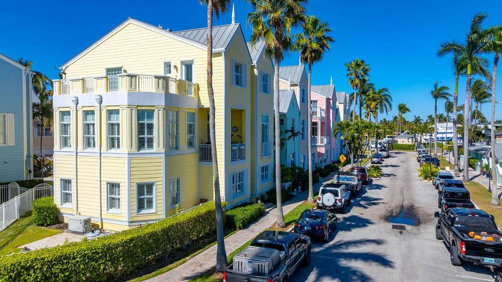 Great opportunity to own one of the largest townhouses in Tillotson Square!  Impeccable SE corner! 3 levels with 5 BR, 3.5 BA & elevator. Bedrooms on the 1st and 3rd floors. The 2nd floor is all living space w/ separate living/family rms, huge kitchen w/ snack bar, formal dining rm + add'l rm being used as bar & a balcony. Enjoy the coastal breezes & stunning views overlooking the LHP Marina and the Intracoastal Waterway beyond. This updated residence features plantation shutters, impact glass, new flooring, generator and a private yard plus a pristine interior. Through the gated entry is a private 2 car garage.  Enjoy socializing at the community pool with club room and at the Naughti Dog restaurant as well as the marina. This is a gem in a sought after complex with a prime location!