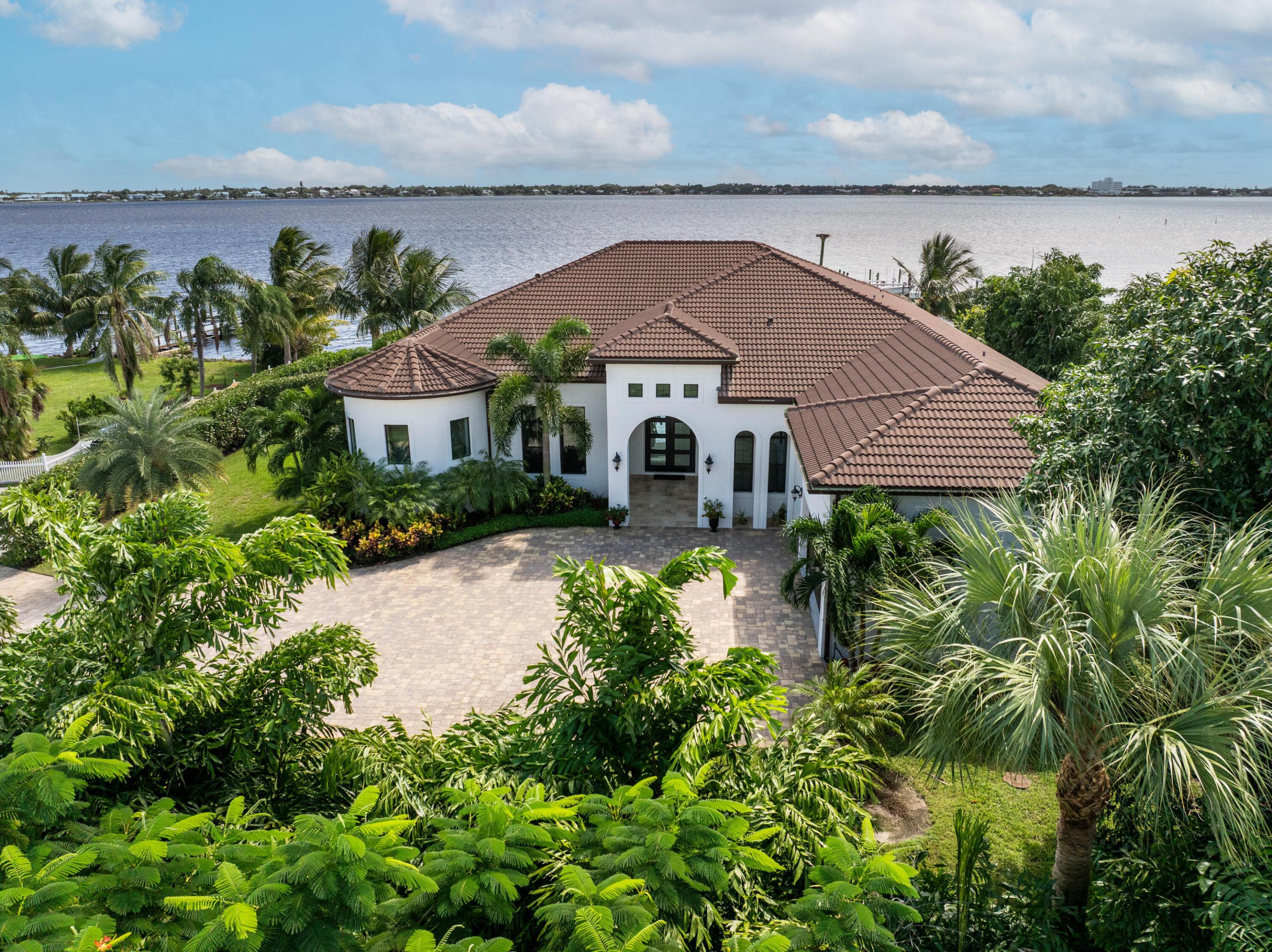 FIRST TIME ON MARKET! Premier waterfront location built in 2020. Modern-Mediterranean home close to downtown Jensen Beach and Stuart. Spectacular southern exposure and wide-water view. Direct ocean access minutes from the St. Lucie Inlet. No low bridges - a boater's dream. High coffered ceilings, four spacious bedrooms plus a den, four full baths, and a cabana bath designed for everyday comfort and effortless entertaining. Gourmet chef's kitchen, top notch appliances, quartzite counters, custom cabinetry, walk-in pantry. Private waterfront with covered dock, two high-speed boat lifts, personal watercraft lift, and lowered platform for kayaks and paddle boards. Room for your yacht or sport-fish. Heated saltwater pool, spa tub, sun shelf, and iridescent glass tile. 3-car garage, impact windows & sliders, huge covered patio, backup generator, 1,000 lb in-ground propane tank. Perfect balance of comfort, convenience, and breathtaking waterfront views. Don't miss your chance to own it!