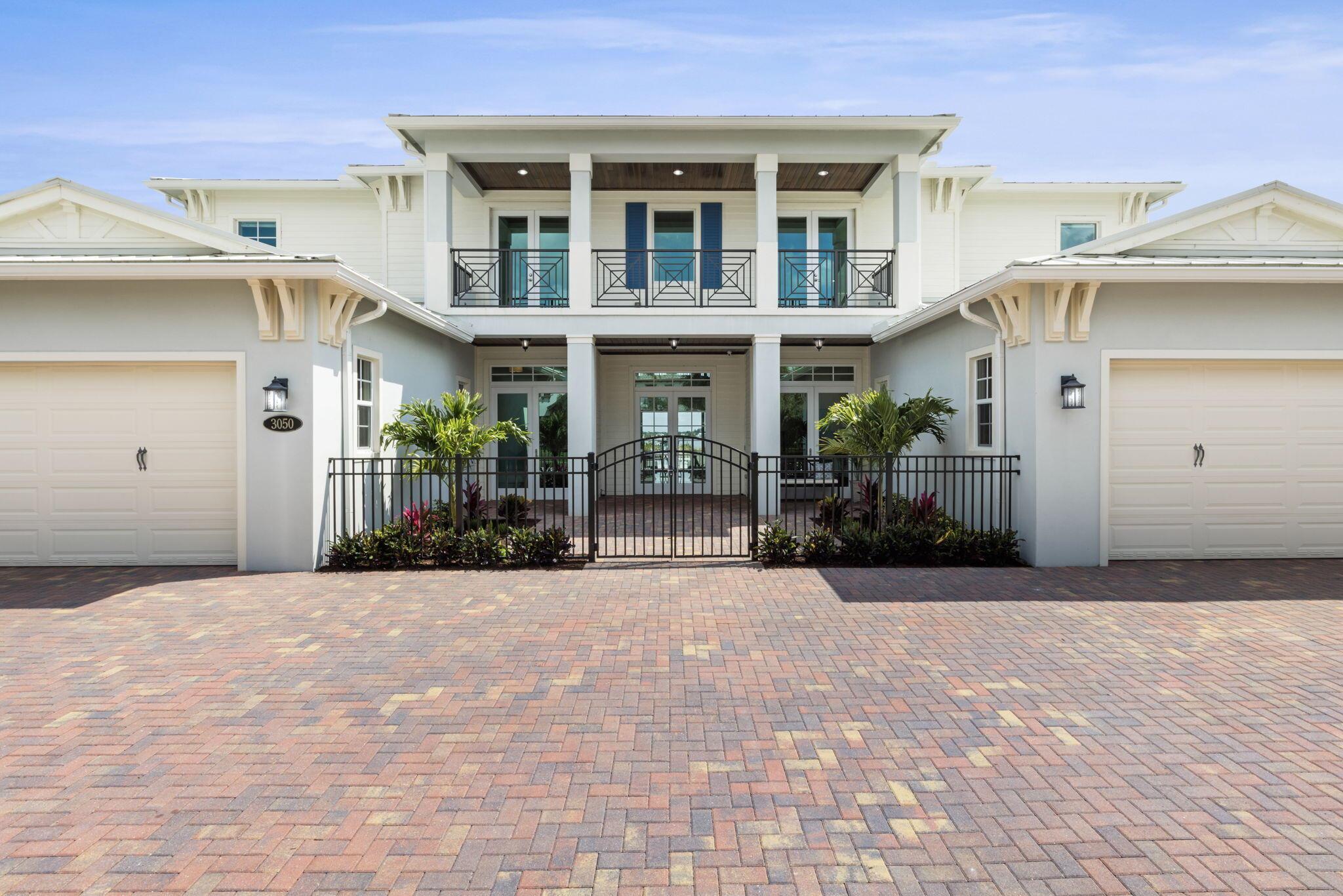 Welcome to a unique opportunity to own waterfront luxury living at its finest. This meticulously designed coastal-style estate is a boater's dream, boasting nearly 6000 square feet of living space with 5 bedrooms, 6.5 baths, and four garage spaces. From the moment you step inside, you'll be greeted by an incredible 30-foot foyer featuring a double curved staircase, setting the tone for the entire home. This estate features custom built-ins, a chef's kitchen with gourmet Sub Zero/Wolf appliances and a large kitchen island, a club room for entertaining with a full kitchen, formal dining and living rooms, and a double-height great room. Additionally find a custom wood elevator, primary master suite with an exceedingly large en-suite, a secondary VIP suite and breathtaking water views from virtually every room. Step outside to an over-sized 3000+ square foot marble deck with a sparkling pool and spa, gas fire feature, outdoor kitchen and grill with custom Tuuci umbrellas, perfect for entertaining. With deep-water access, a 16,000 lb boat lift at the end of the beautiful dock, and a 48KW generator included, this property offers fun adventures on the water with all the security and convenience. The boutique community features a guard gate, 47 estate homes, a beautiful entry bridge and its own day dock. Just 5 minutes from i95, 10 minutes from fine dining, and 45 minutes from PBI airport, waterfront paradise awaits you in the boutique enclave of Riverbend.