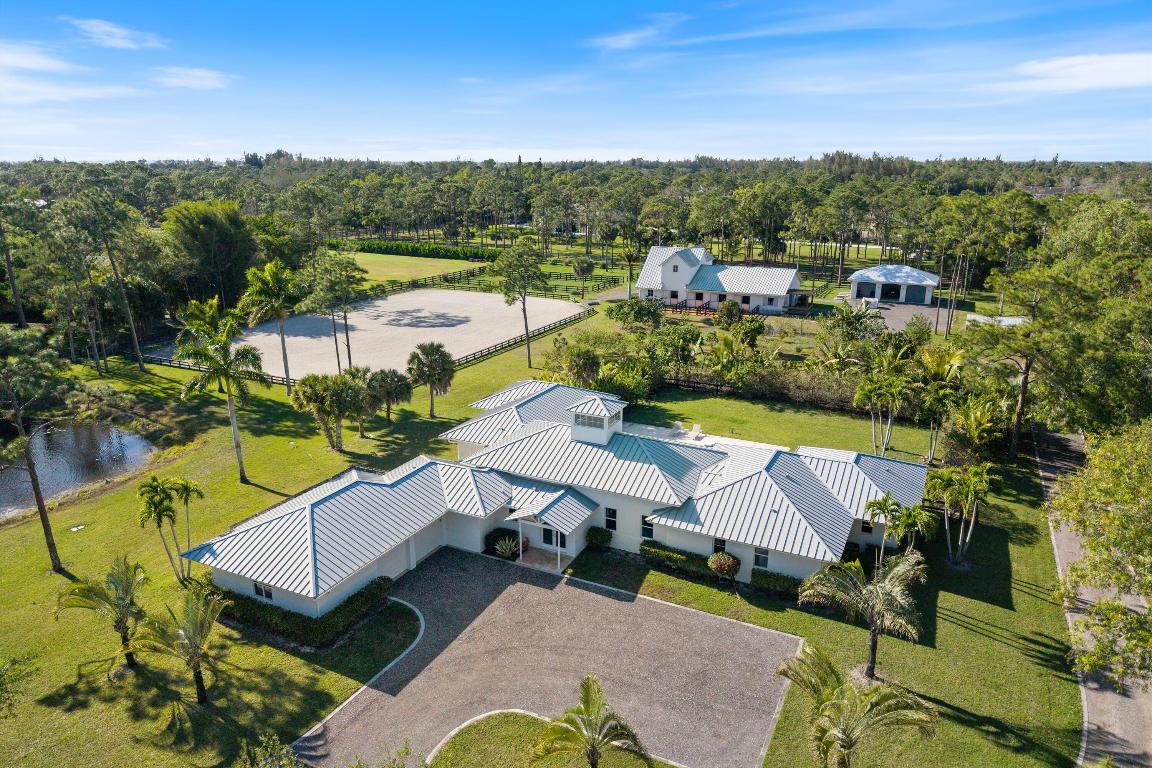 Nestled in the serene, gated equestrian community of Homeland, this exceptional 5-acre property includes a luxurious main residence, private pool, a new barn and arena, a detached garage building plus a lounge with full kitchen and bath! Located at the beginning of the community, yet tucked away on a private lot near the end of a quiet street, makes this home have the perfect balance of tranquility and convenience. Equestrian amenities include a NEW barn, featuring 7 (potentially 8) 12x12 stalls (one of them being even larger), complete with runouts to 3 of the stalls. Designed with form and function in mind, the barn has rubber flooring throughout, stunning tongue-and-groove ceilings,
tack and feed room, barn bathroom, water access to each stall, fans and a fly spray system. Additionally, an oversized arena (approx 200x130) with premier GGT footing and proper drainage was recently installed by IDA. 5 grassy paddocks in various sizes provide ample space for turnout, with the potential to add more.
The barn also includes a separate, oversized 3-car garage/storage building perfect for housing hay, shavings, tractor and jumps! Above the barn you will find a charming lounge with a newer kitchen and bathroom.
The expansive main residence was completed in 2015 and boasts 4,159 square feet of meticulously designed living space. It offers 3 spacious bedrooms + a 4th bonus room, 3 full and one half-bath. With flexibility and comfort in mind, 2 of the bedrooms are large primary suites that is each located on its own wing of the house. They are completed with sitting areas, luxury closets, spacious bathrooms and private entries to the outside pool area. The third bedroom also includes an ensuite, large marble bathroom with a walk in closet. The home offers an open concept, indoor/outdoor living with gorgeous vaulted ceilings, custom lighting and hurricane impact glass throughout. The modern kitchen is equipped with a gas stove and large island, followed by a half bath and a walk-in pantry.

There is a separate laundry room, a 2-car garage plus a bonus room off of the garage with plumbing and its separate entrance, that could serve as a 4th bedroom! Enjoy Florida's sunny days from your private covered patio, or take a dip in the beautiful in-ground pool overlooking the park-like grounds. The property is fully fenced for privacy, has a pond with a fountain, chicken coop and a large, very impressive fruit orchard with many exotic trees like mango, papaya, banana, lychee, avocado, dragon fruit, starfruit, pomegranate and more. No details were spared on the mature landscaping around the premises with plenty of exotic, rare and highly valuable trees as well.
 There are 2 wells for the property, one for the barn and house and one for irrigation. A new RO system has just been put in.
Just minutes from horse shows & turnpike, and with direct access to the bridle path with lengthy riding trails, this is a rare opportunity to own an extraordinary equestrian estate with newer construction in one of the most sought-after neighborhoods in the area.

DISCLAIMER: All information provided to you regarding this Property by Realtor and his/her associates has been obtained from third parties such as the Multiple Listing Service, public records and other sources. All Buyers should independently verify all information provided regarding this Property. The Sellers, Realtor and Broker make no representation as to the accuracy of this information. All Buyers should perform their own independent due diligence regarding this Property before executing a Contract for Sale and Purchase for this Property.