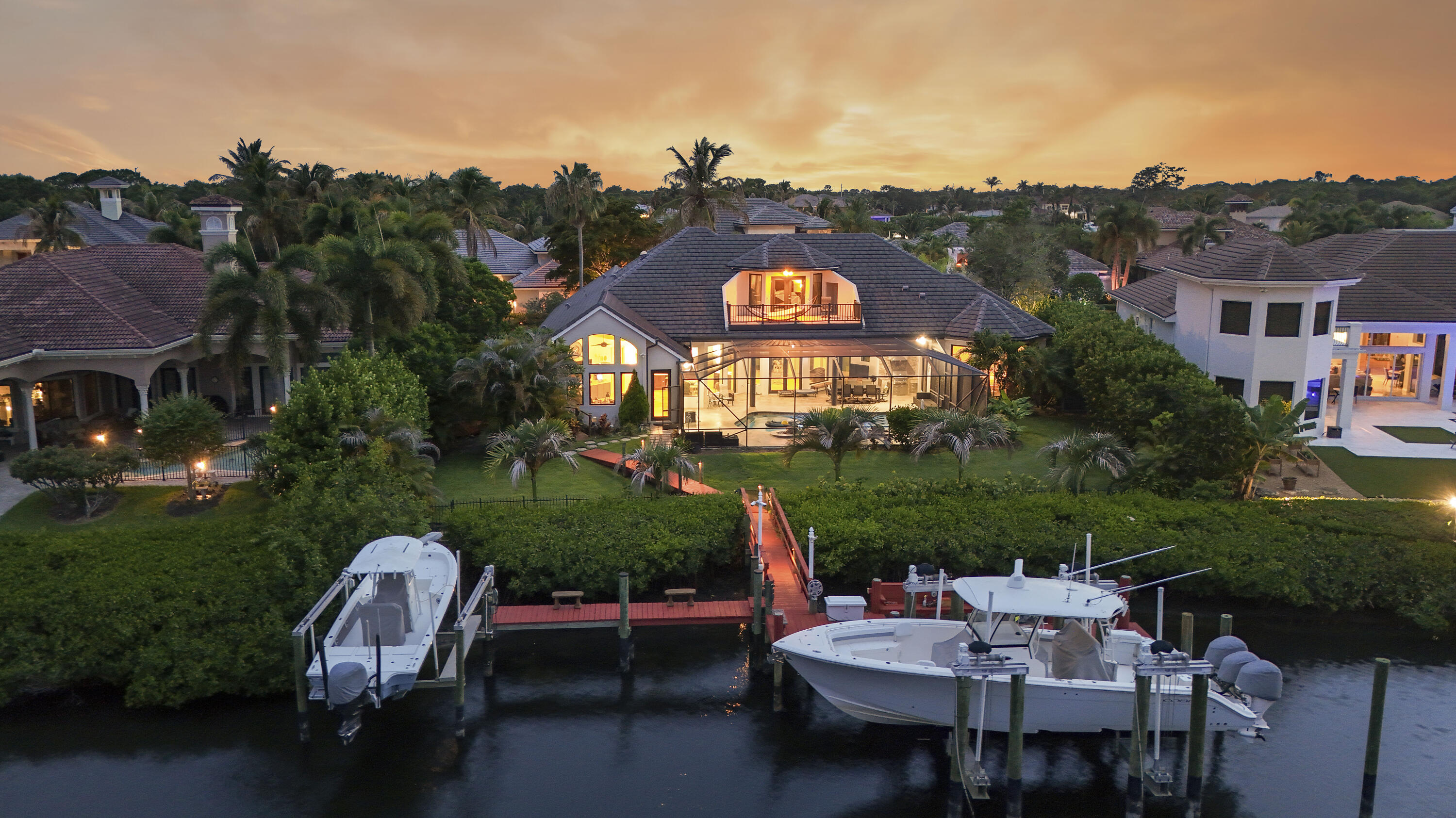 Experience the ultimate South Florida waterfront lifestyle in the prestigious, gated Islands of Jupiter—a private waterfront community comprised of approximately 105 custom estates spread across four islands, renowned for its exclusivity, deep-water access, and prime location in the heart of Jupiter.   Situated on 100 feet of deep-water frontage with no fixed bridges, this exceptional estate offers direct ocean access in approximately 10 minutes and a private dock accommodating 2-3 boats.  Spanning 4,648 square feet, the home features a thoughtfully designed split floor plan with 4 bedrooms, 5 baths, a bonus room, and a rare 4-car garage. The main level showcases an expansive primary suite and two guest suites, while the upstairs VIP retreat offers  a sitting area, wet bar, and private bal cony with tranquil river views.  Designed for effortless indoor-outdoor living, the backyard is a private oasis complete with a resort-style pool and spa, screened patio, outdoor kitchen, and cabana bath. The desirable eastern rear exposure captures refreshing ocean breezes and keeps the outdoor living spaces cool and comfortable throughout the afternoon—an ideal setting for year-round entertaining and relaxation.  Recent upgrades include a new roof, beautifully renovated kitchen, fresh interior and exterior paint, a porcelain-paver driveway, and impact windows and doors throughout. A secluded setting, full-house generator, and whole-home water filtration system complete this move-in-ready waterfront retreat, where luxury, privacy, and premier boating access come together in one of Jupiter's most coveted boating communities.