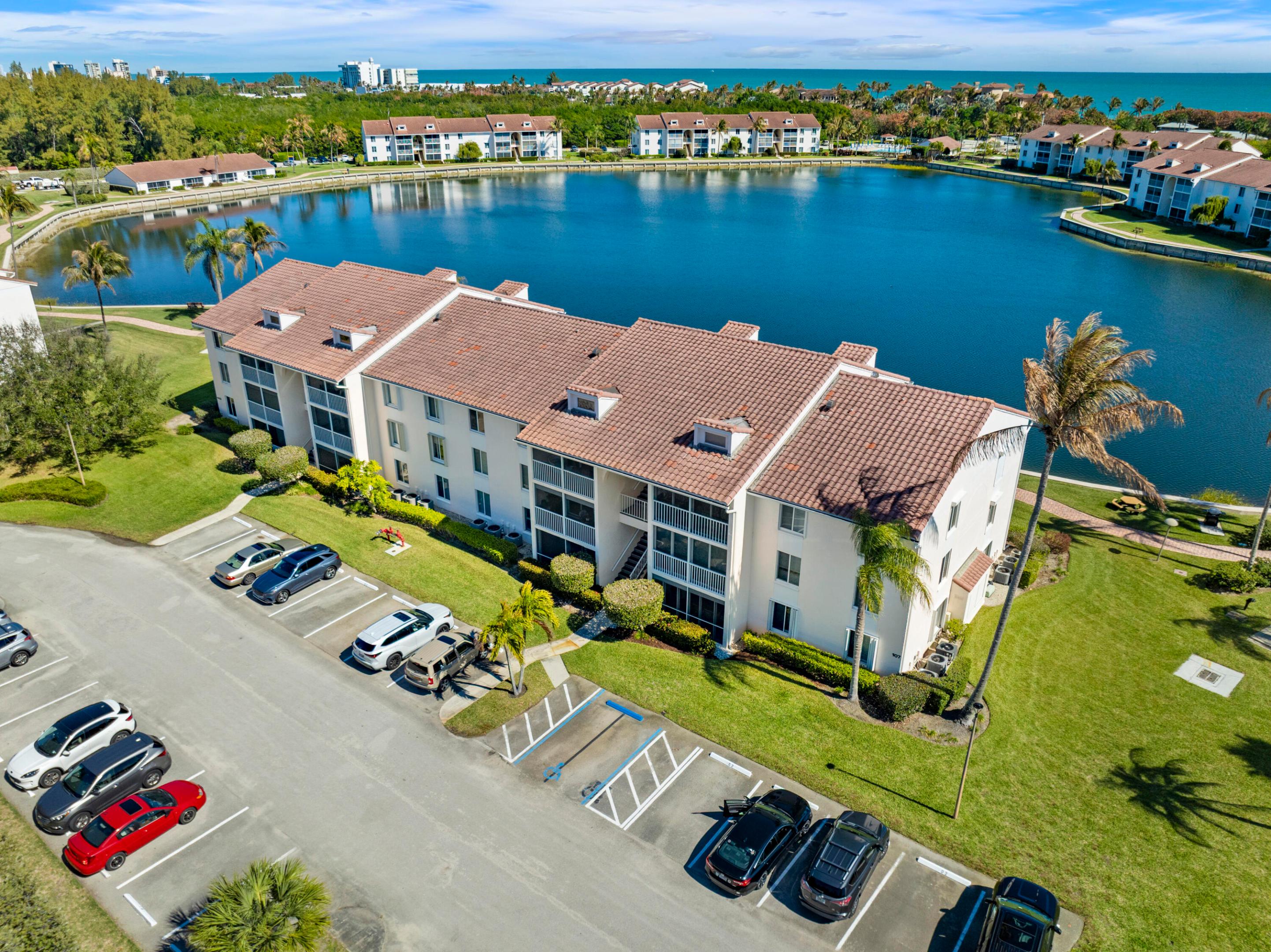 Island Living at Its Best--just a short walk to the beach! This furnished 2BR/2BA third-floor condo in Jensen Beach Club is located directly across from the beach and offers a light-filled coastal retreat. Vaulted ceilings and tile flooring throughout the main living areas create an open, airy feel, while the carpeted primary bedroom adds comfort and warmth. The spacious layout is functional and ready for your personal touches.  Unwind on your screened balcony overlooking a tranquil natural setting. The gated, pet-friendly community (one small pet up to 25 lbs) spans over 7 acres and features a stocked freshwater lake for fishing, along with resort-style amenities including a heated pool, spa, clubhouse, pickleball, tennis, bocce, and shuffleboard.