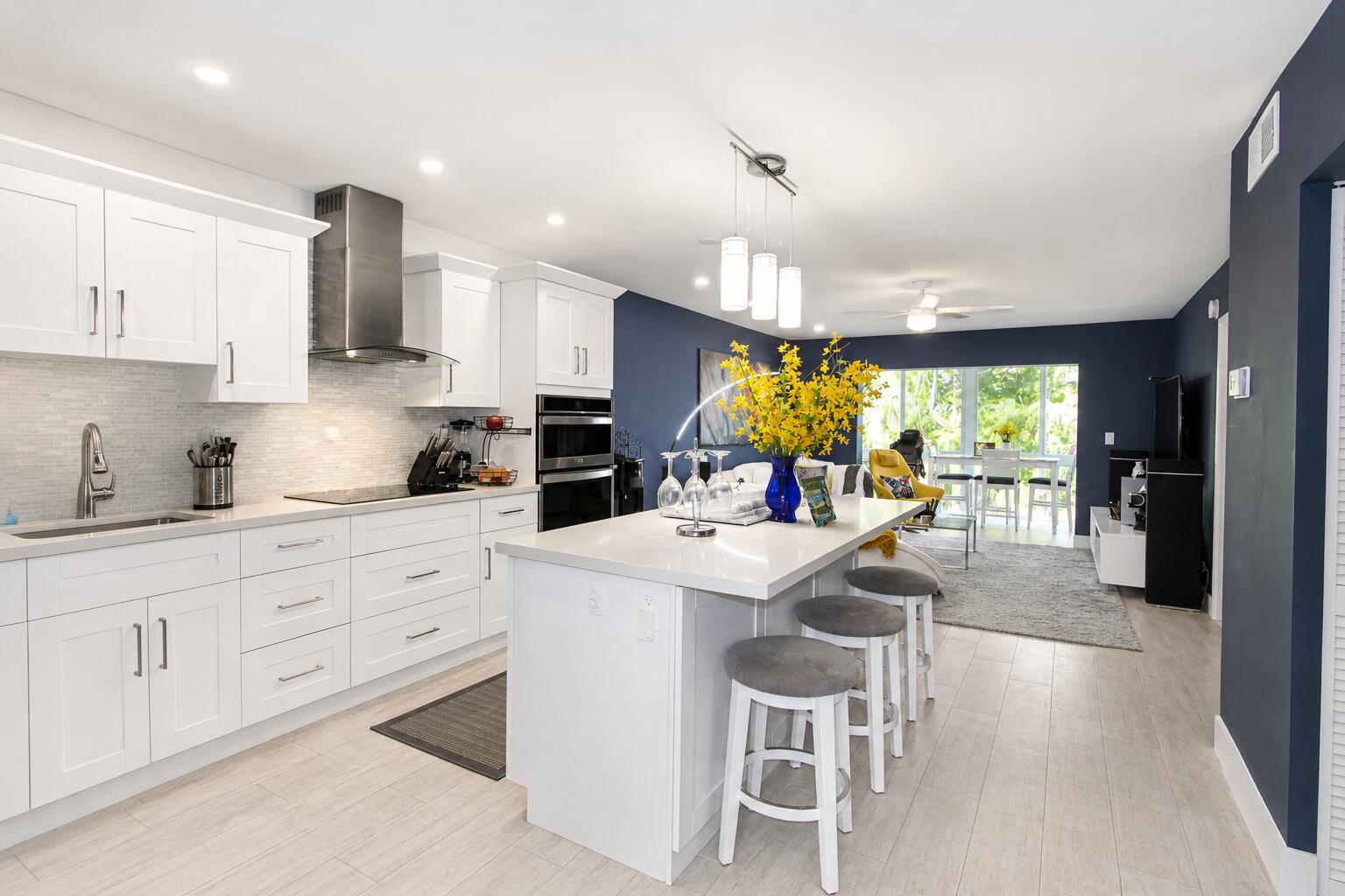 Move-in ready and beautifully remodeled, this 2-bedroom, 2-bath corner condo is located in an extremely quiet and well-maintained 55+ community with peaceful golf course views. Designed with a bright open-concept layout, this stunning residence features all tile flooring throughout, impact windows, recessed LED lighting, five-inch baseboards, fresh interior paint, white shaker cabinetry, quartz countertops, a large island, and high-end stainless steel appliances. The entire renovation was fully permitted, offering quality craftsmanship and peace of mind. Additional upgrades include custom closets, a smart thermostat, Ring alarm motion sensor at the entry door, and security features installed on the windows.  Enjoy breathtaking sunrise views each morning from the spacious enclosed  patio while sipping your coffee and overlooking the serene golf course. Conveniently located directly across from the community amenities, residents enjoy access to a clubhouse, community room, fitness center, sauna room, library, billiards, pool, shuffleboard, picnic area, bike storage, additional storage, and more. Plenty of guest parking is available for visitors.  The HOA includes water, basic cable, and WiFi, adding even more value and convenience. The building has successfully completed its 40-year certification. A rare opportunity to own a fully updated in one of the community's most peaceful and desirable locations.